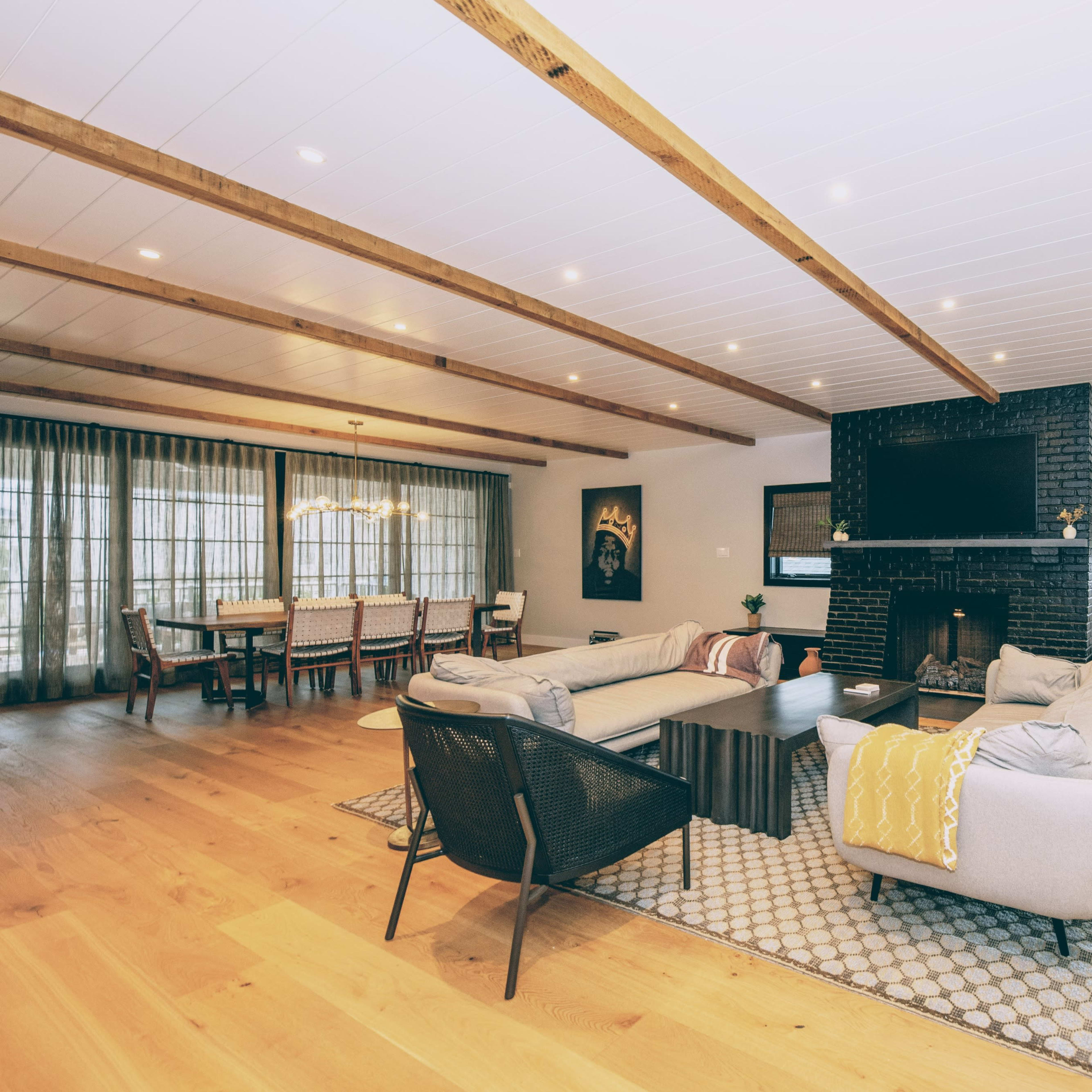 A spacious modern living room with hardwood flooring, a large sectional sofa, a fireplace, and a dining area in the background.