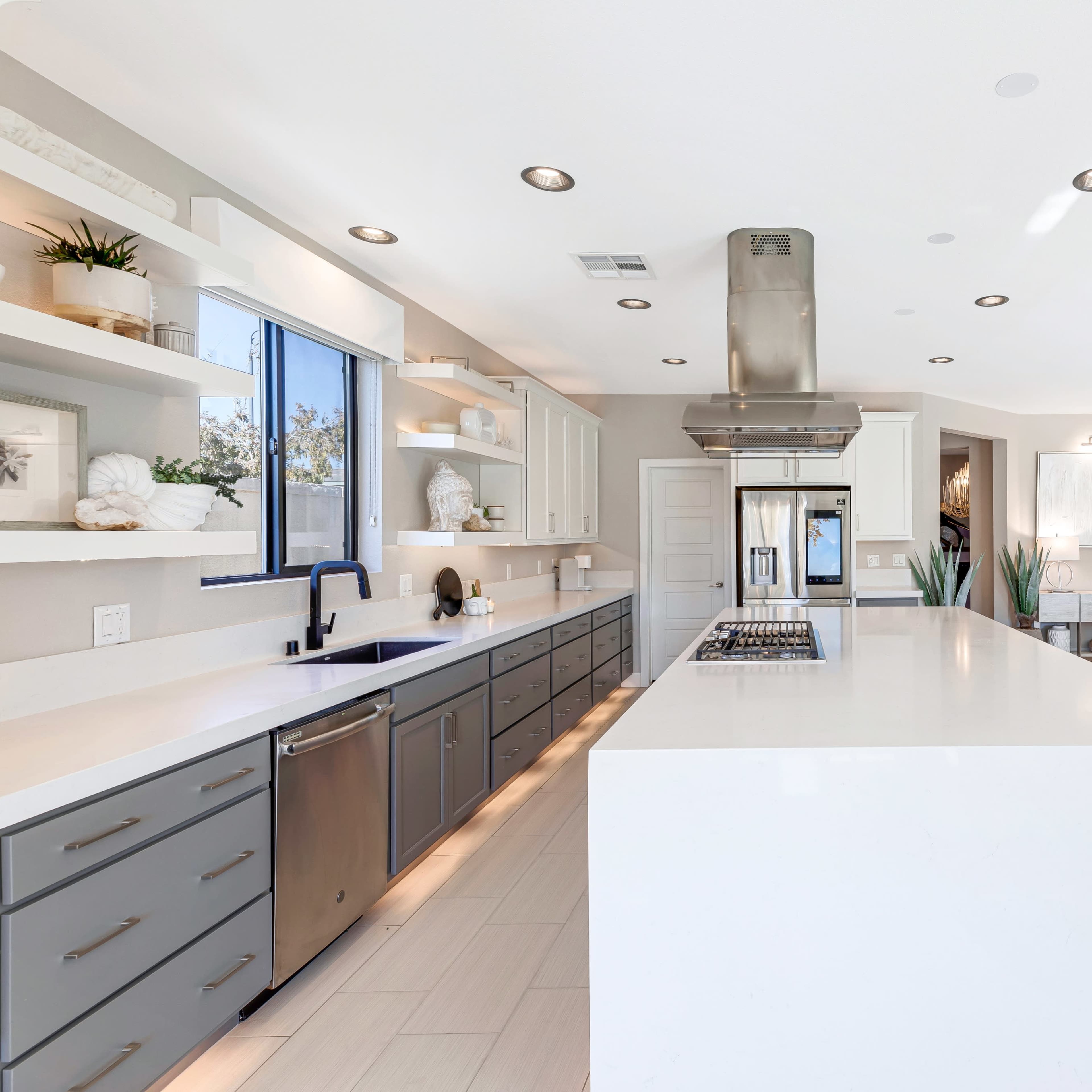 A modern kitchen with gray and white cabinetry, a large central island, and a stainless steel range hood.