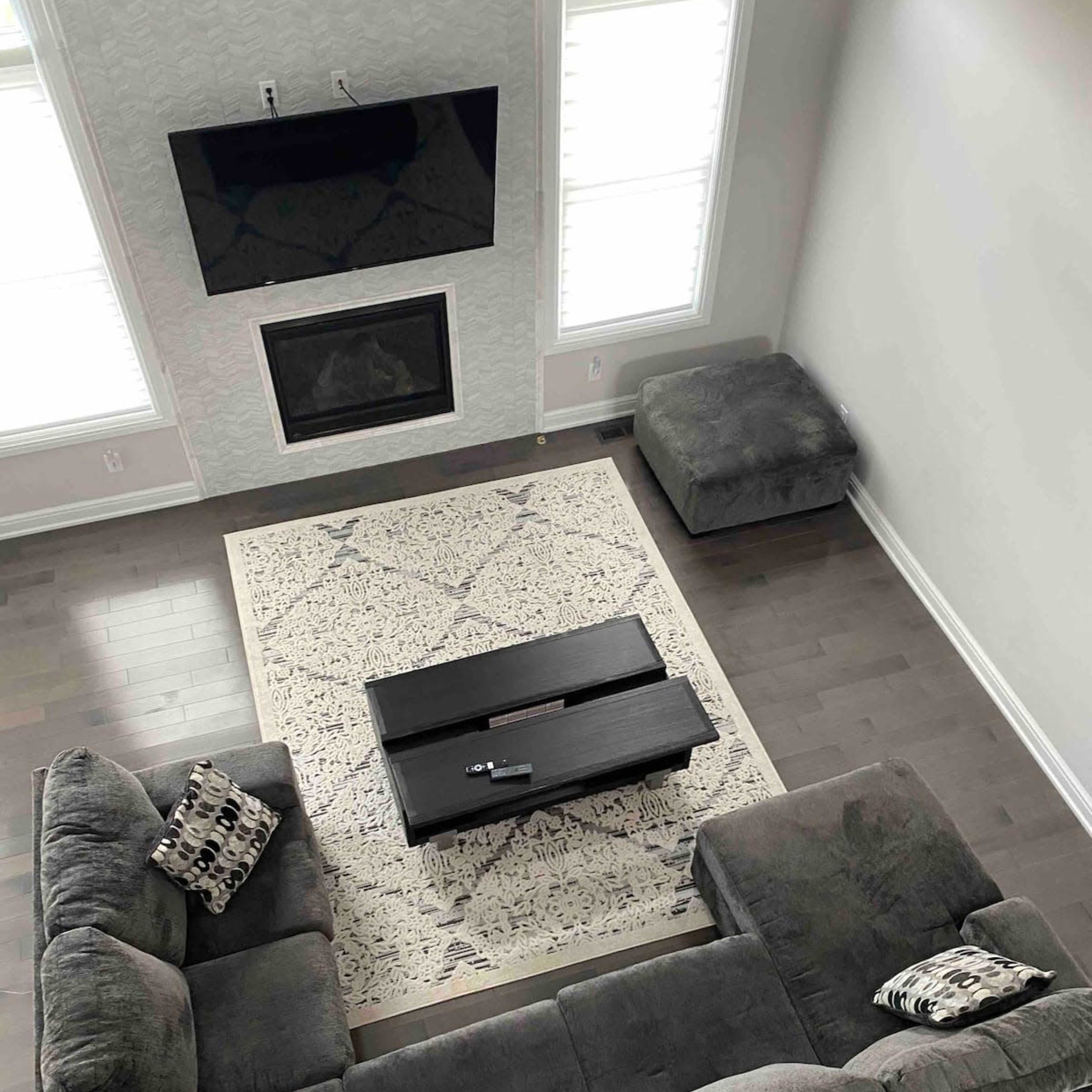 A modern living room with a sectional couch, a coffee table, and a television mounted on the wall.