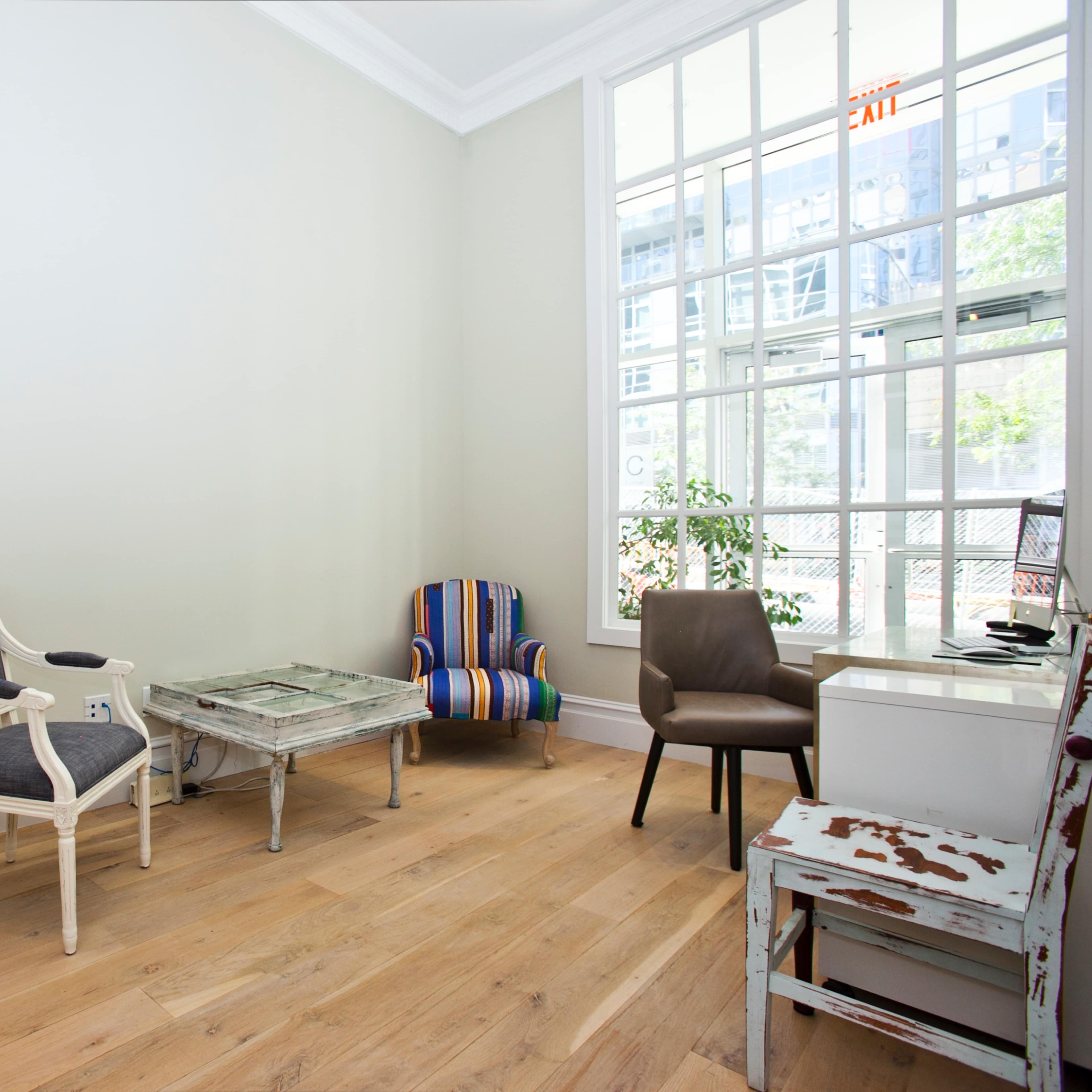 A modern waiting area with a variety of seating options, including a striped chair, a gray chair, and a glass coffee table, alongside a map decor on the wall.