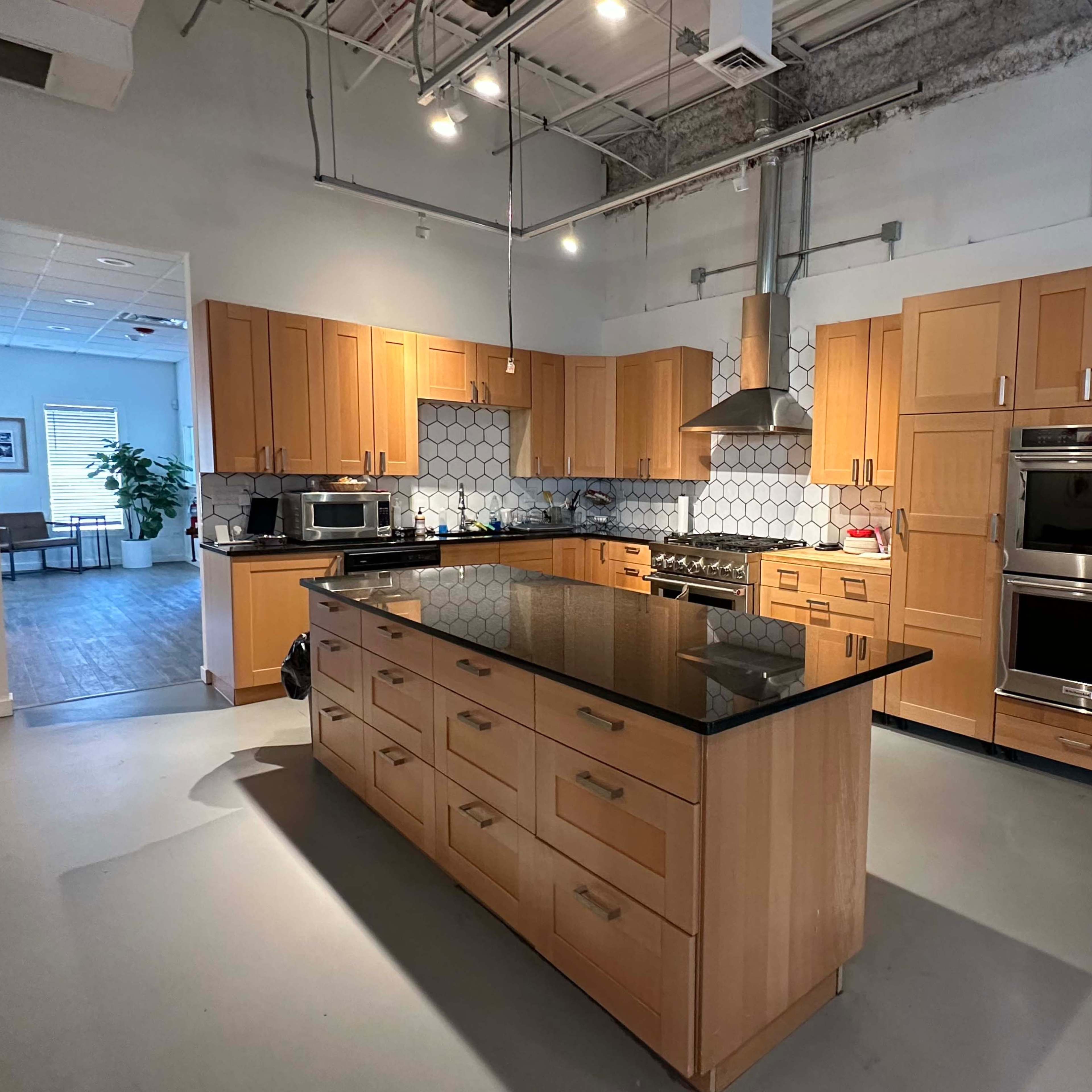 A modern kitchen with a central island, wooden cabinets, stainless steel appliances, and a hexagonal tile backsplash.