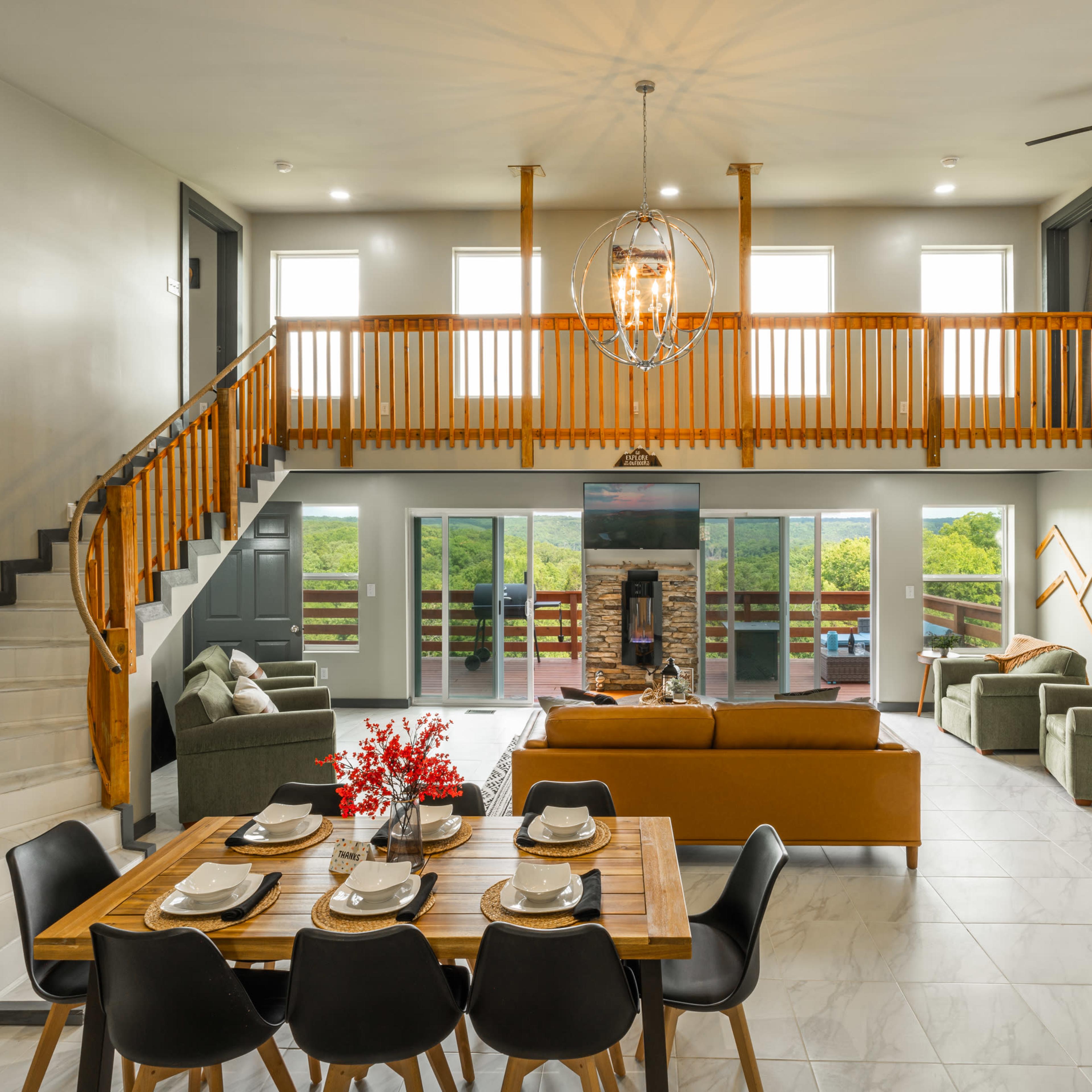 A modern open-concept living area and dining space featuring a wooden dining table, a sectional sofa, and large glass doors leading to an outdoor area.