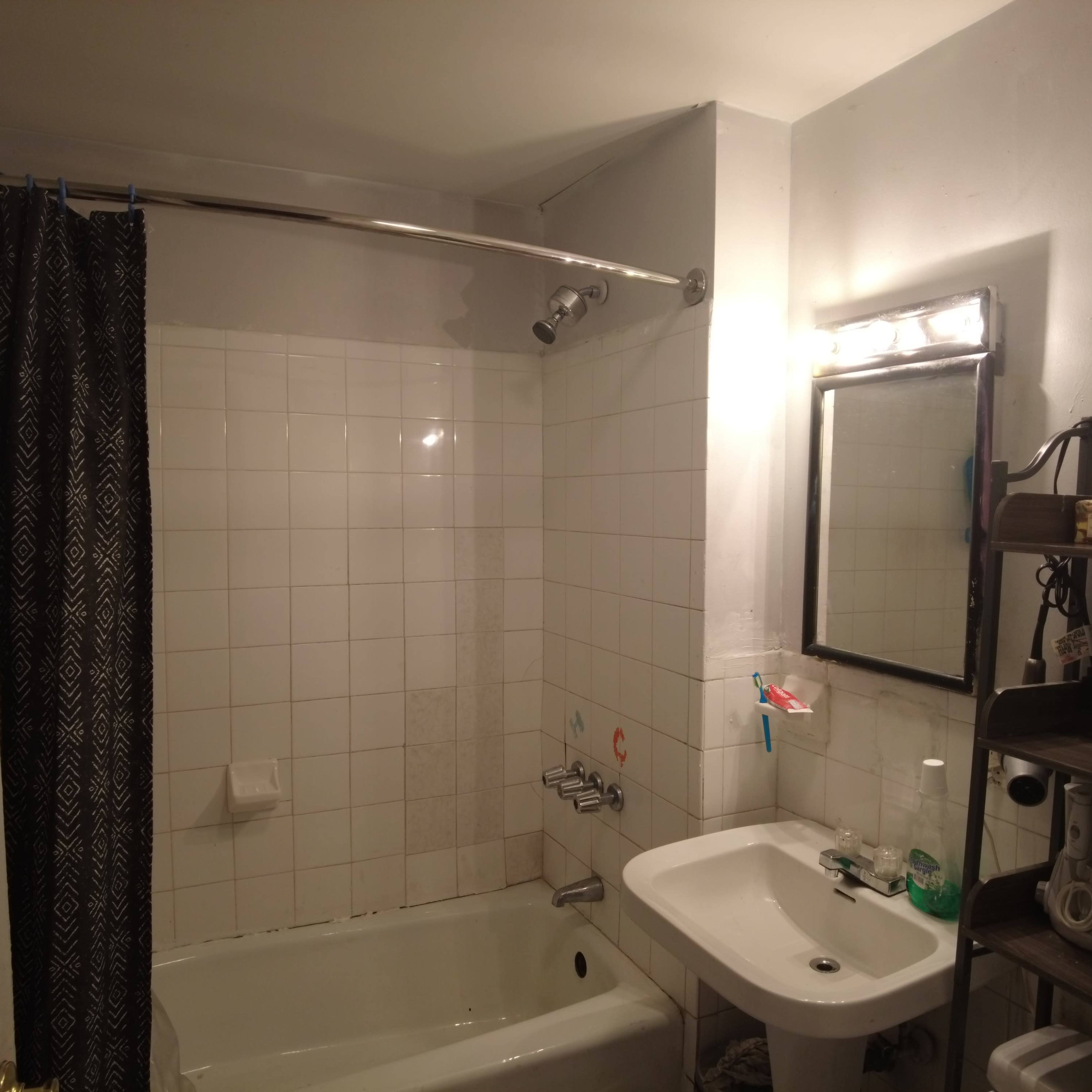 A small bathroom with a bathtub, a sink, a mirror, and a shower curtain.