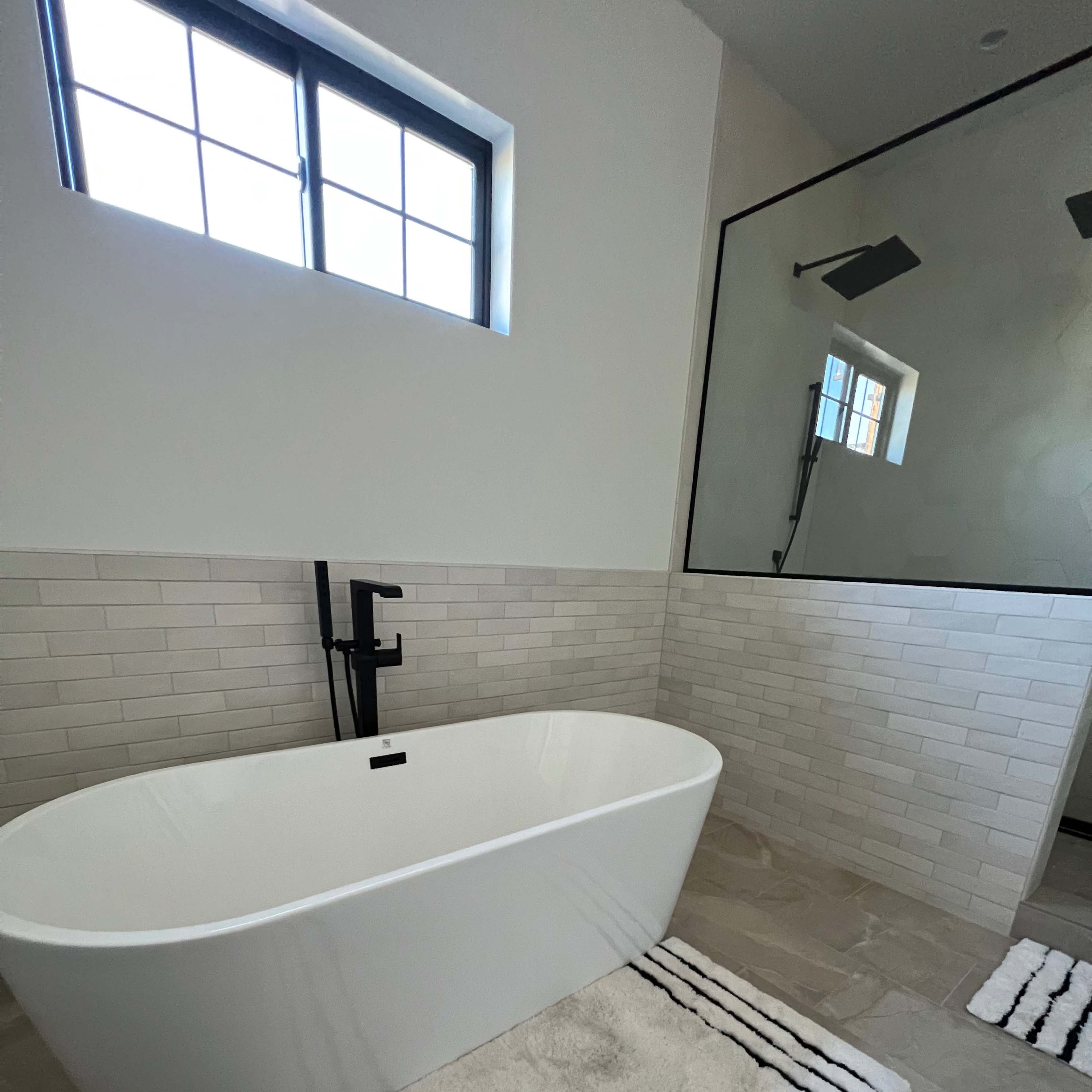 A modern bathroom featuring a freestanding bathtub, tiled walls, and a glass shower enclosure with a rainfall showerhead.