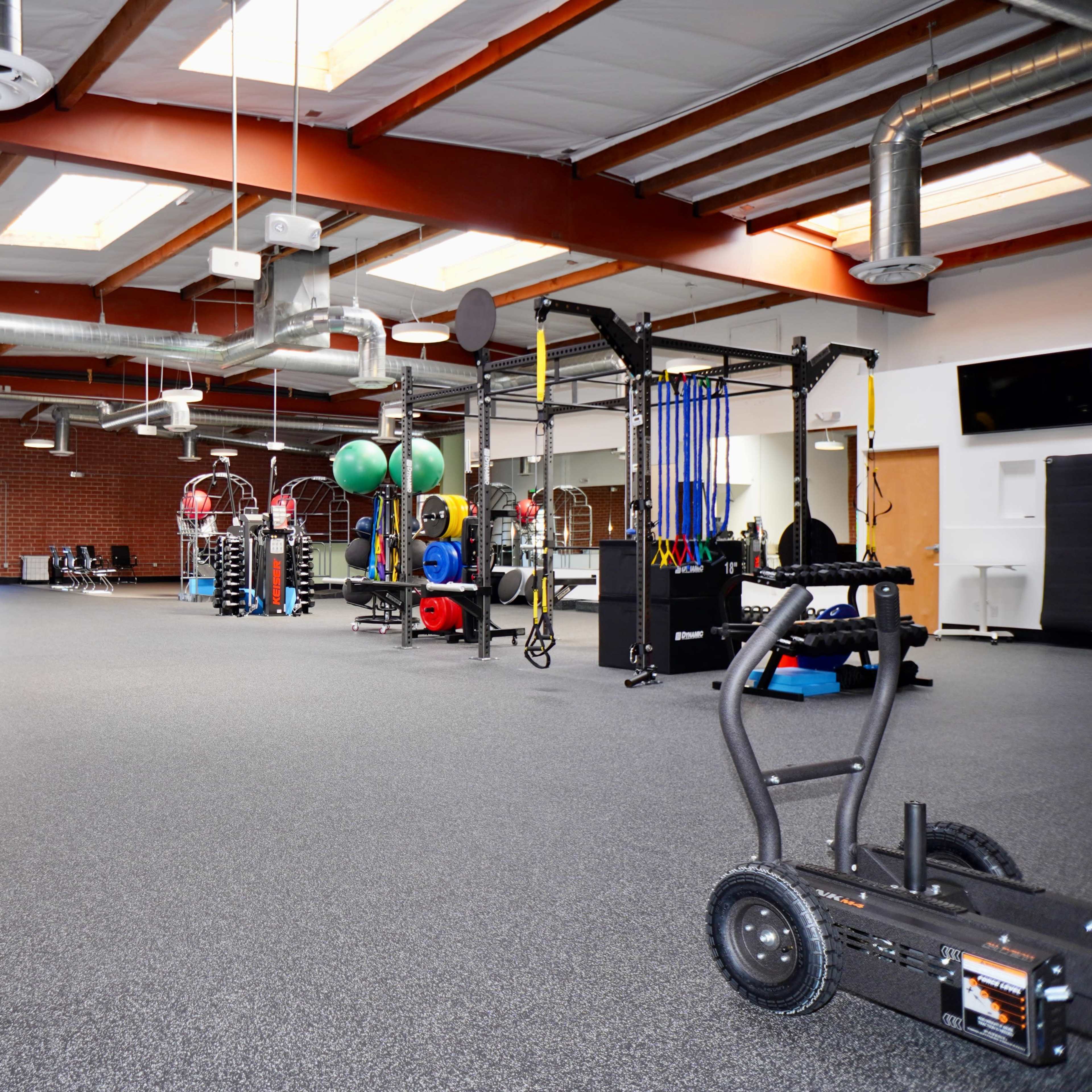A spacious gym interior equipped with various fitness machines, weights, and training equipment.