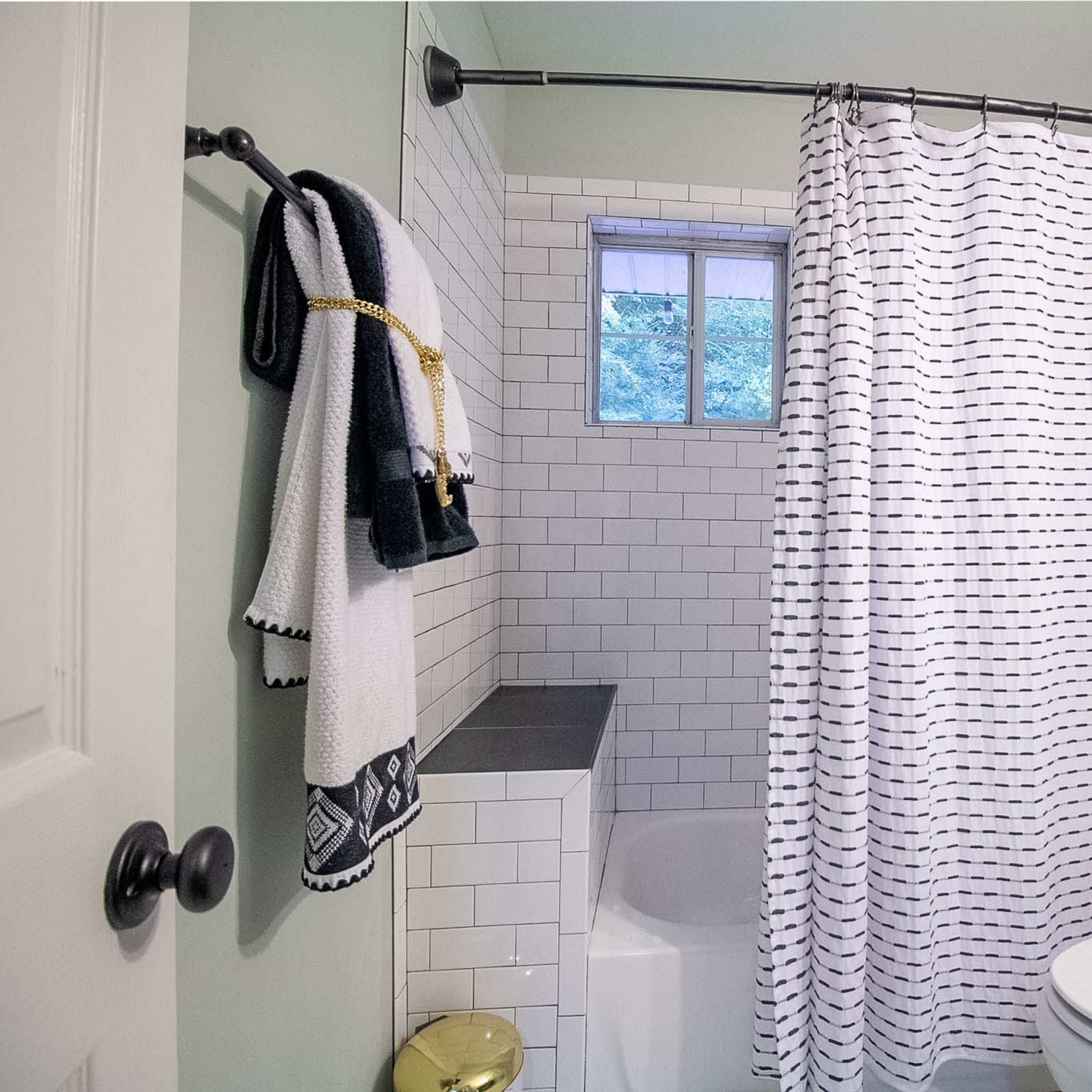 A compact bathroom features a bathtub with a shower curtain, a toilet, and a window for natural light.