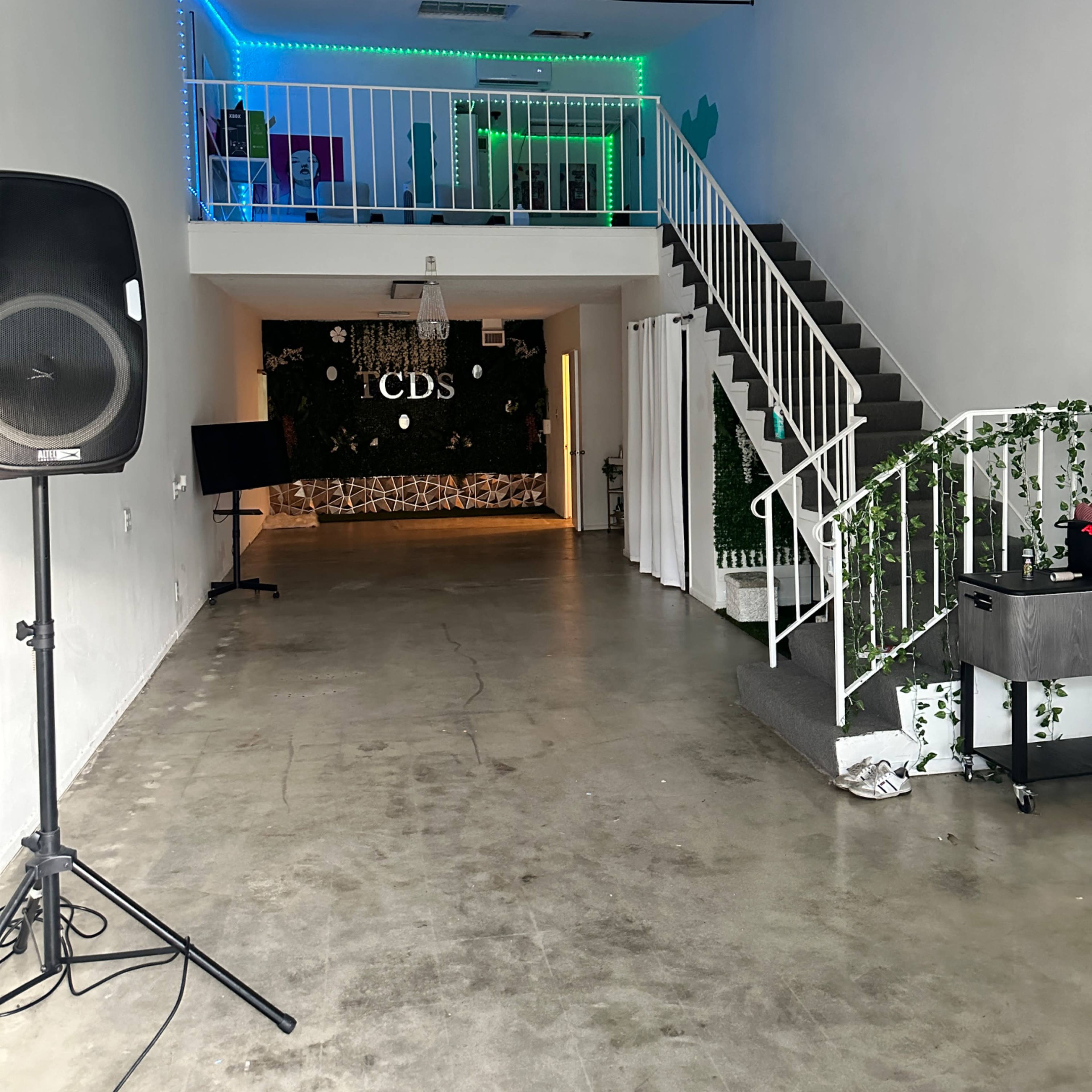 An interior space featuring a staircase, green and blue LED lights, and a wall adorned with greenery.