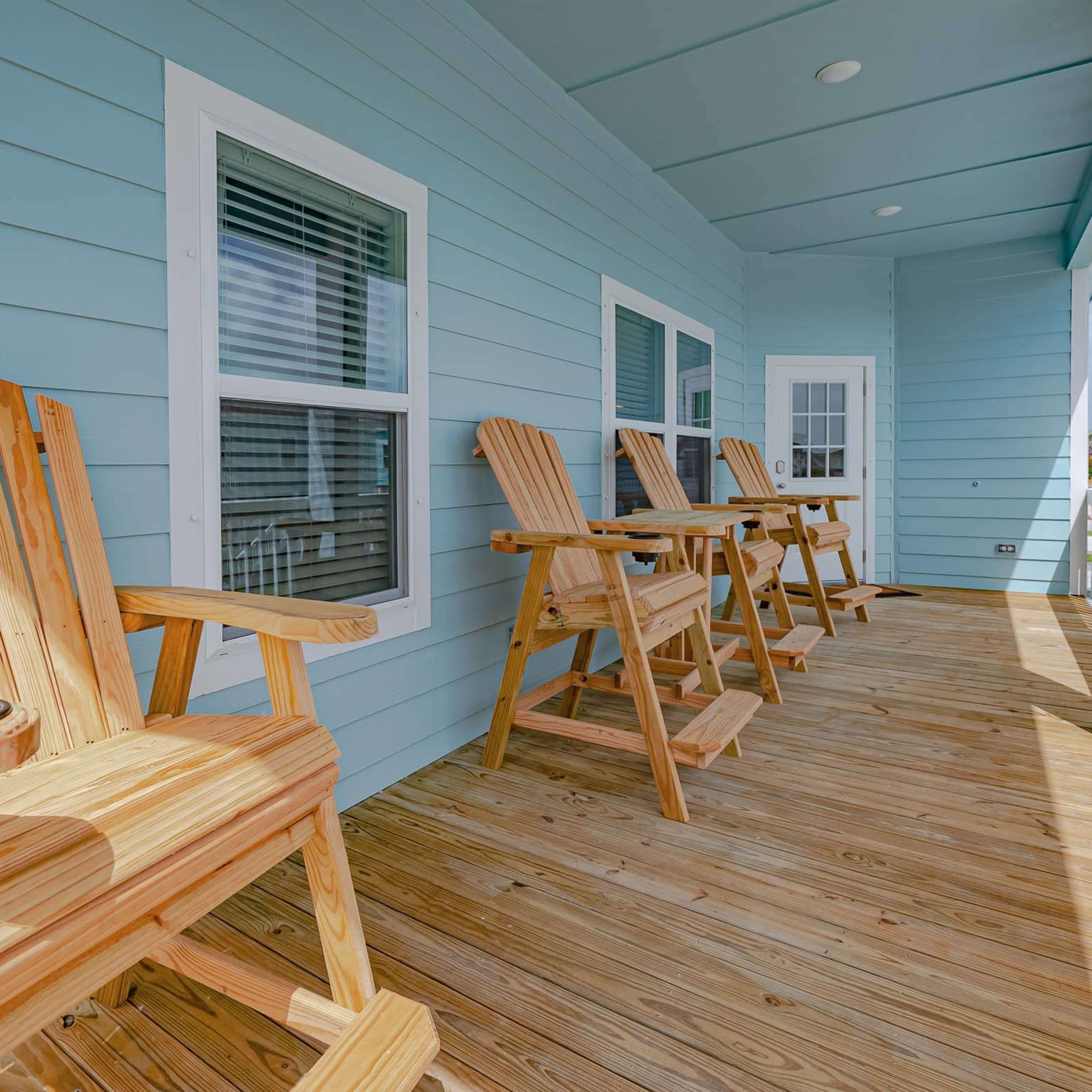 A wooden deck with several tall chairs arranged along a light blue wall.