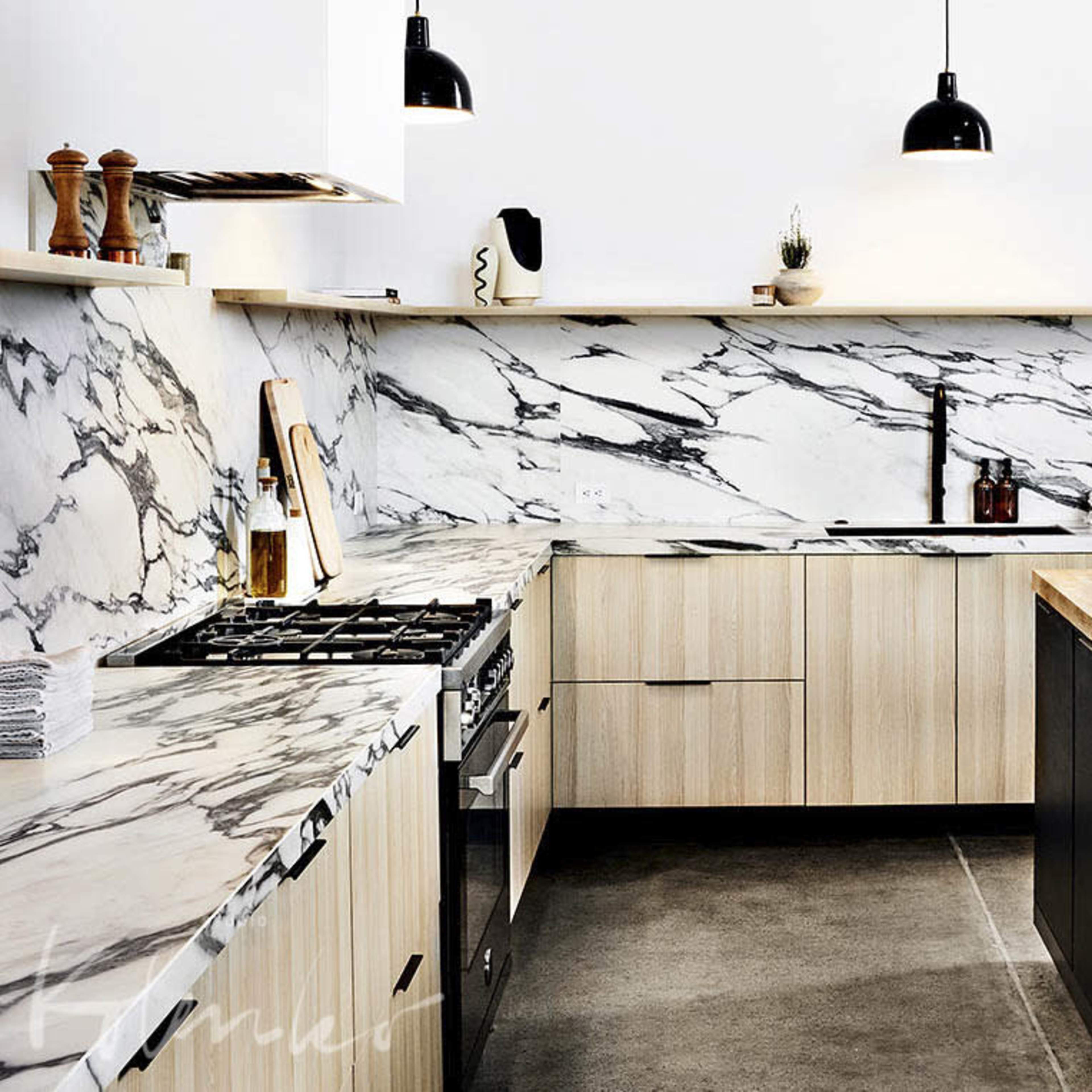 The kitchen features a marble backsplash, wooden cabinetry, and a central island with a butcher block top, complemented by black appliances and pendant lighting.