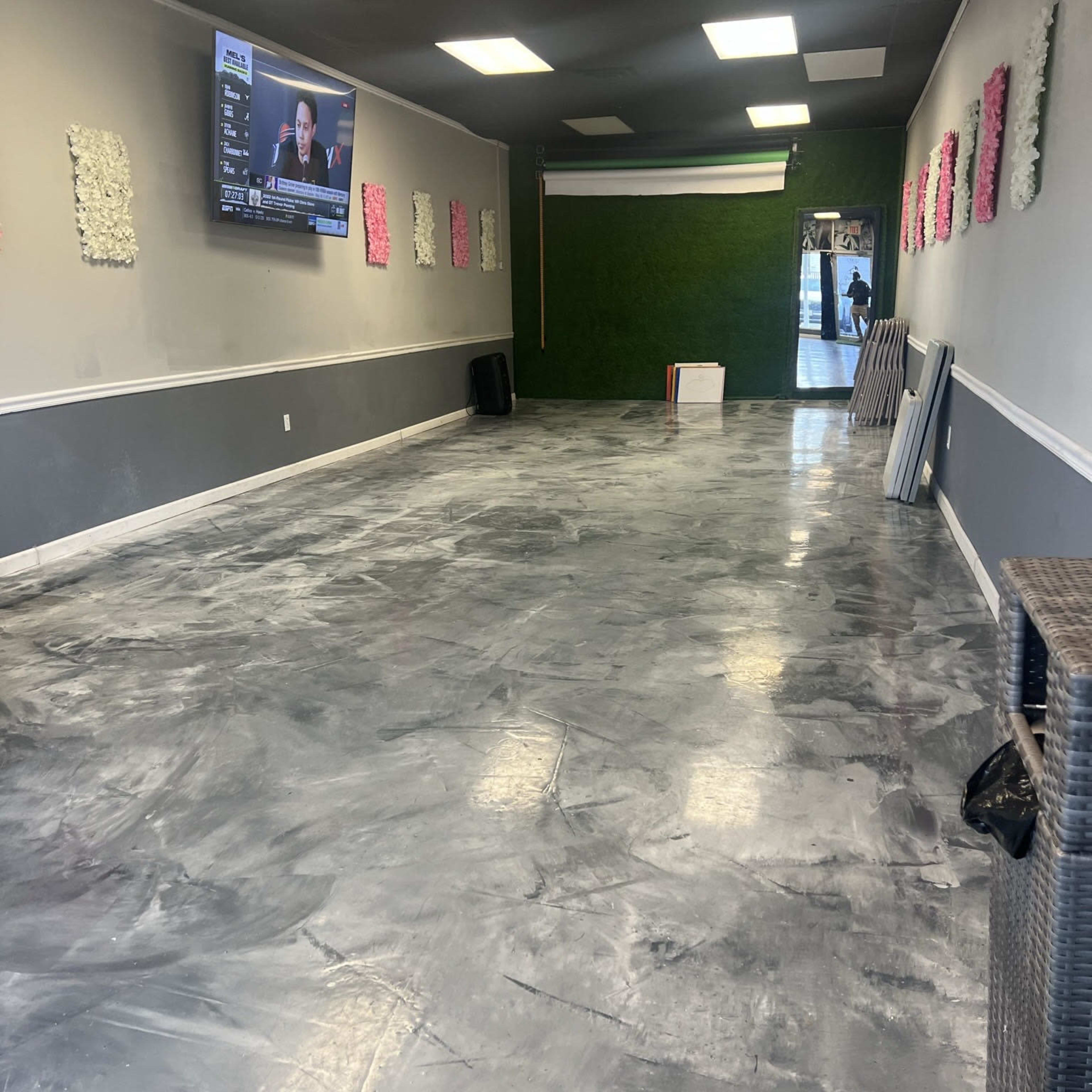 An empty room with a polished concrete floor, decorated with wall panels and a television mounted on one wall.