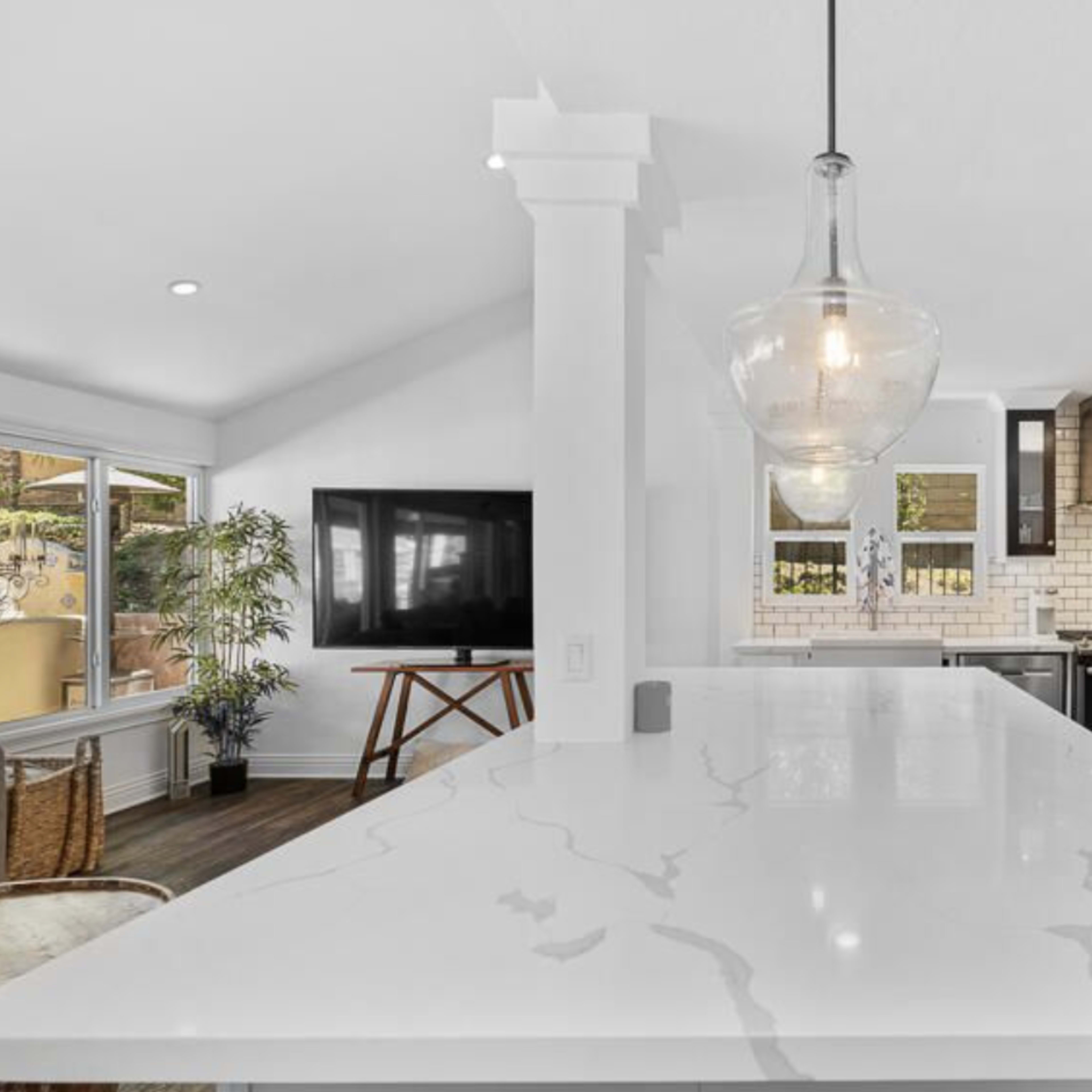 A modern kitchen features a large island with a marble countertop, sleek cabinetry, and stainless steel appliances.