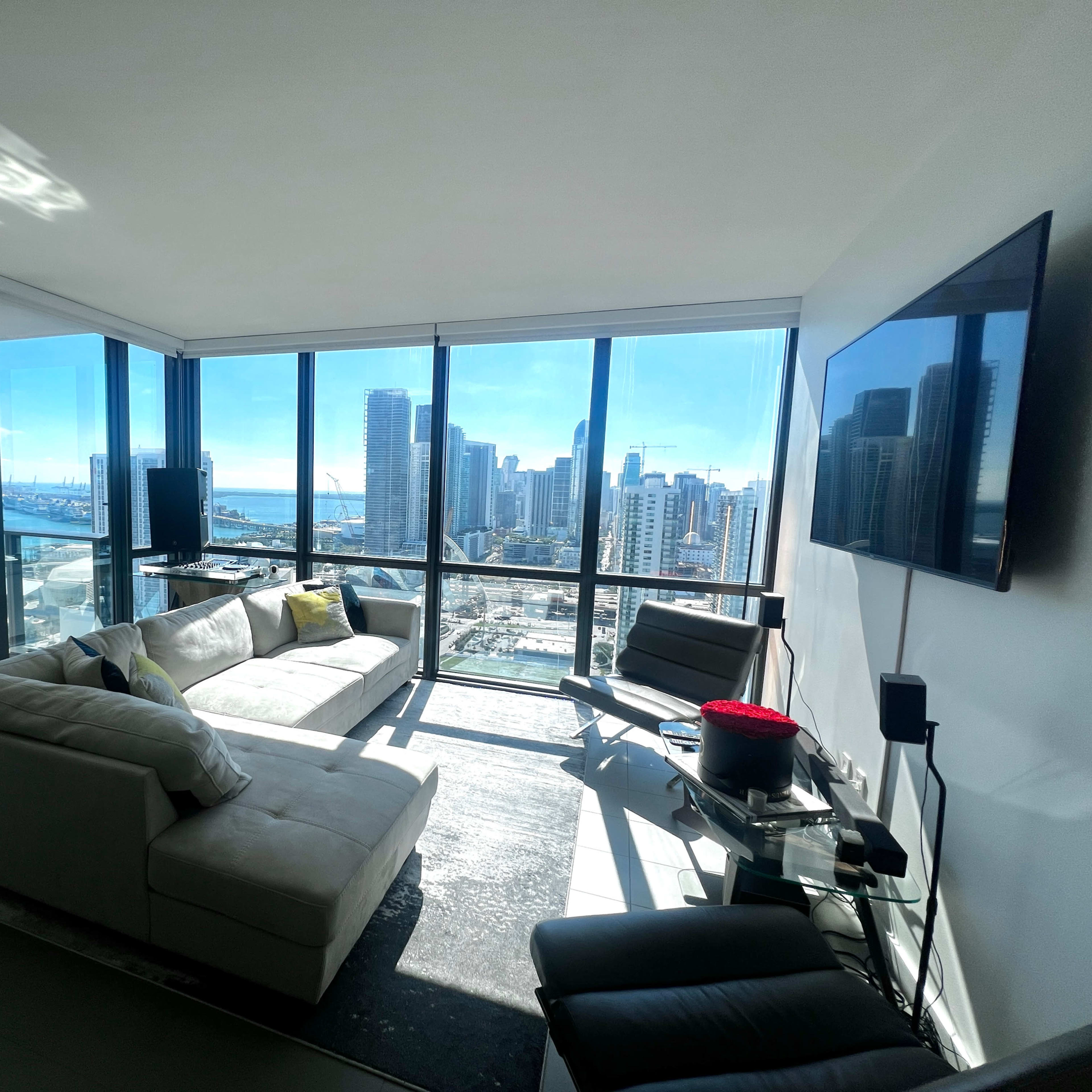A modern living room features large windows with a panoramic view of a city skyline and waterfront.