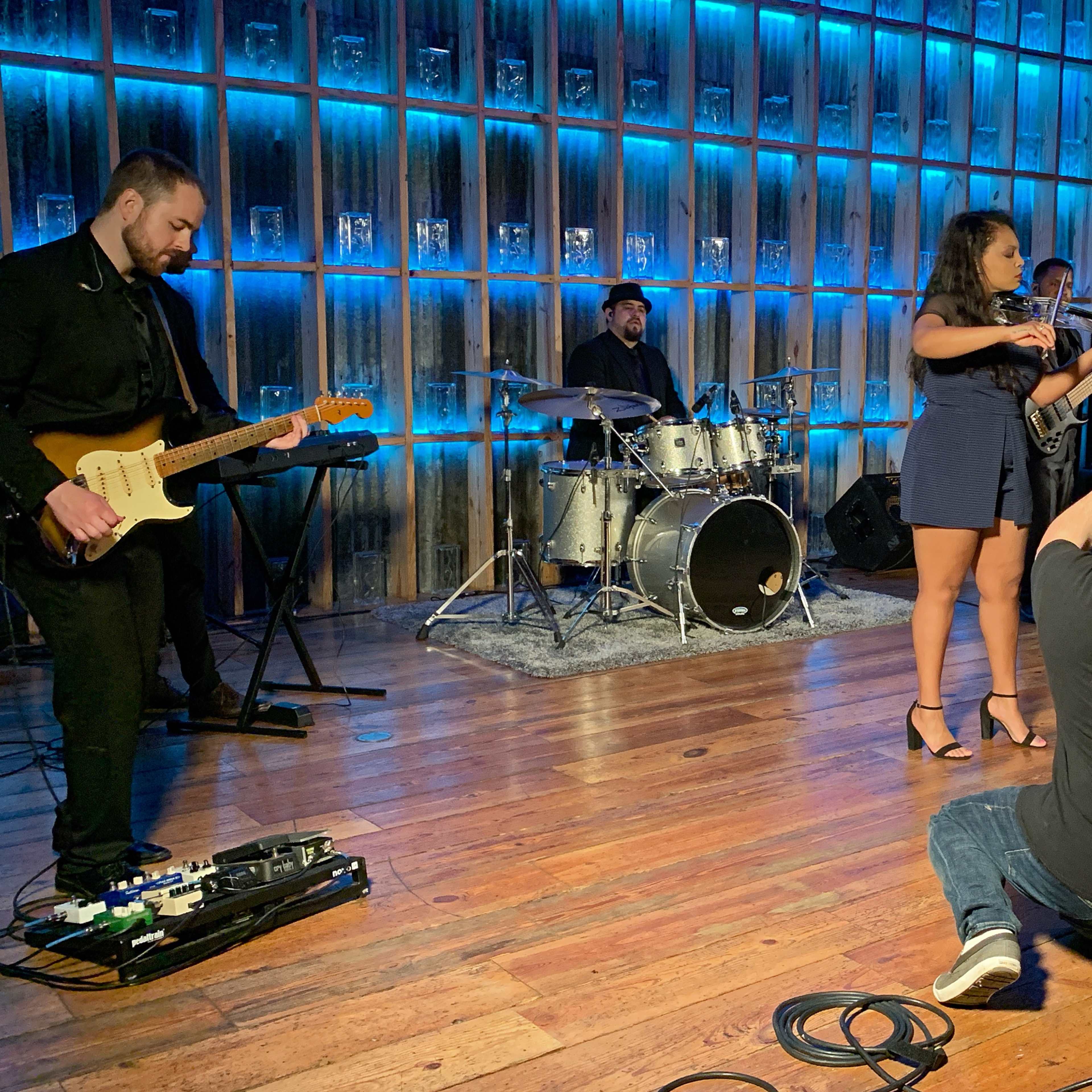 A band performs on stage while a photographer captures the moment in a well-lit venue.