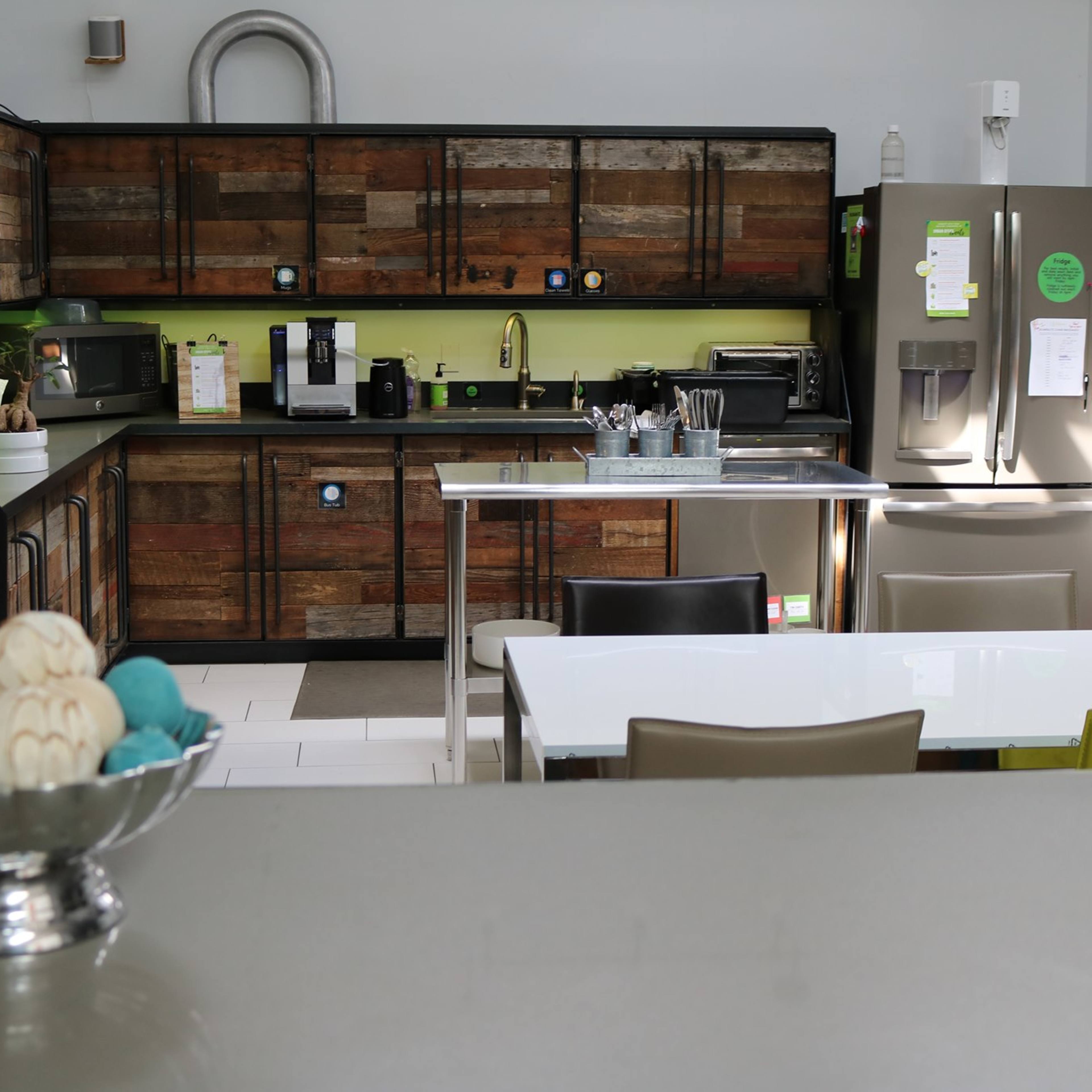 A modern kitchen with wooden cabinets, a stainless steel refrigerator, and a dining table in the foreground.