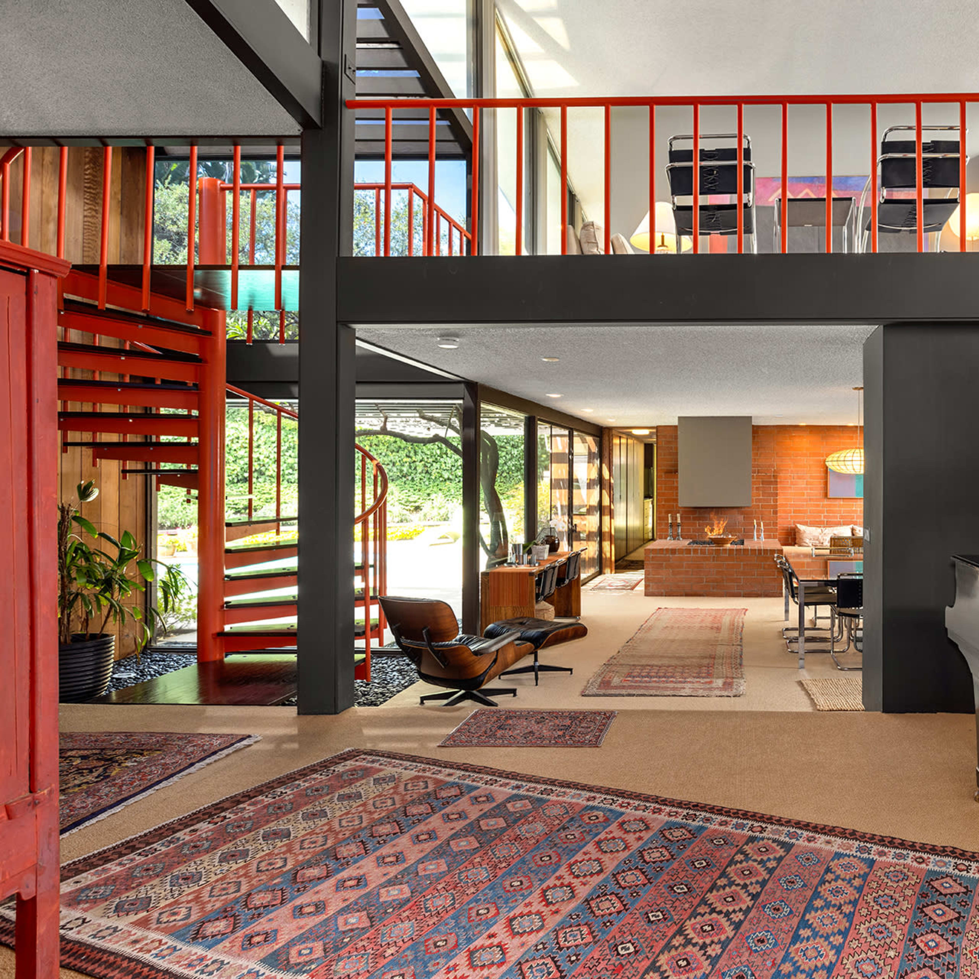 The interior features a modern open-concept space with a staircase, a grand piano, and a view of the dining area through large windows.