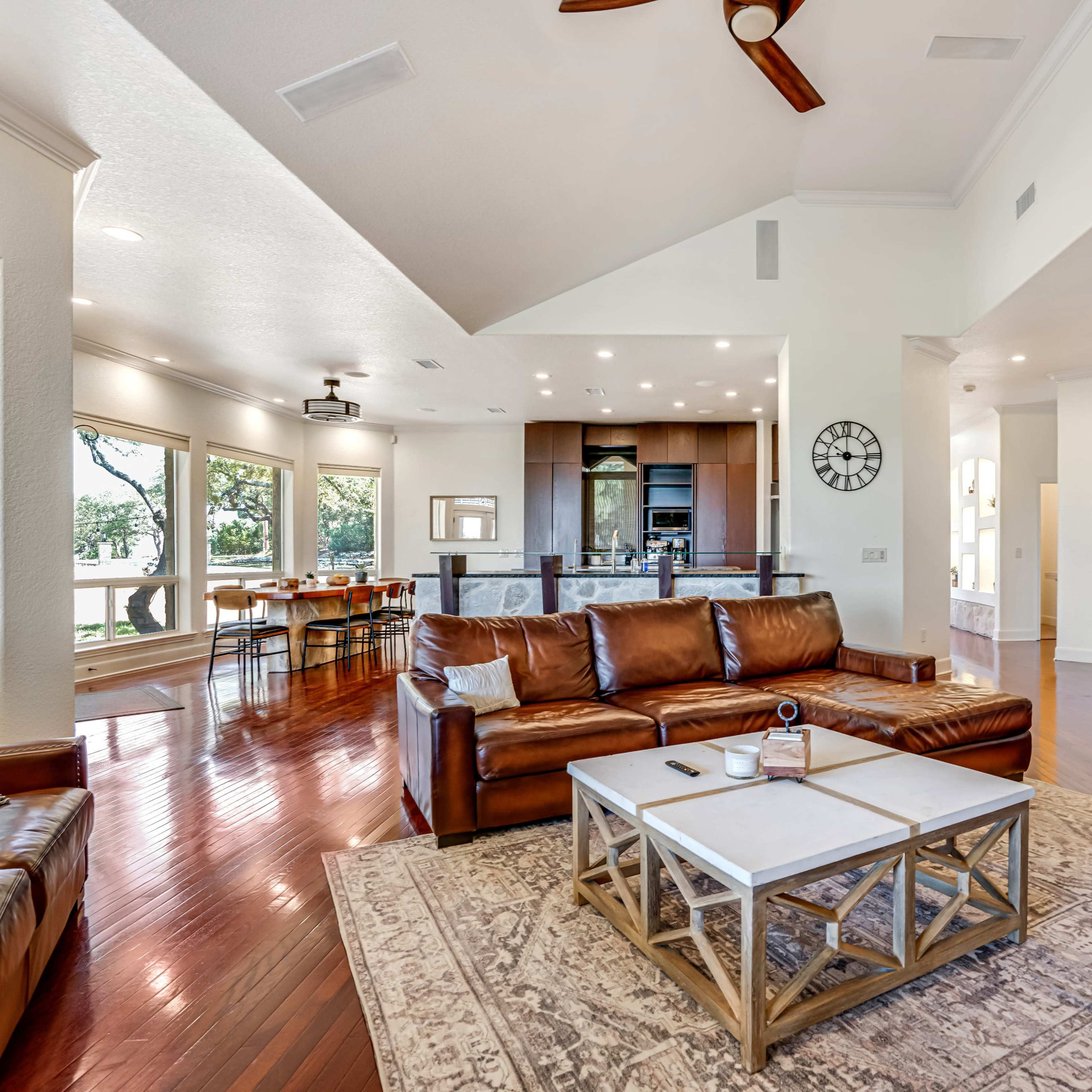 A spacious living area with leather furniture, a coffee table, and large windows that offer a view of the outdoors.