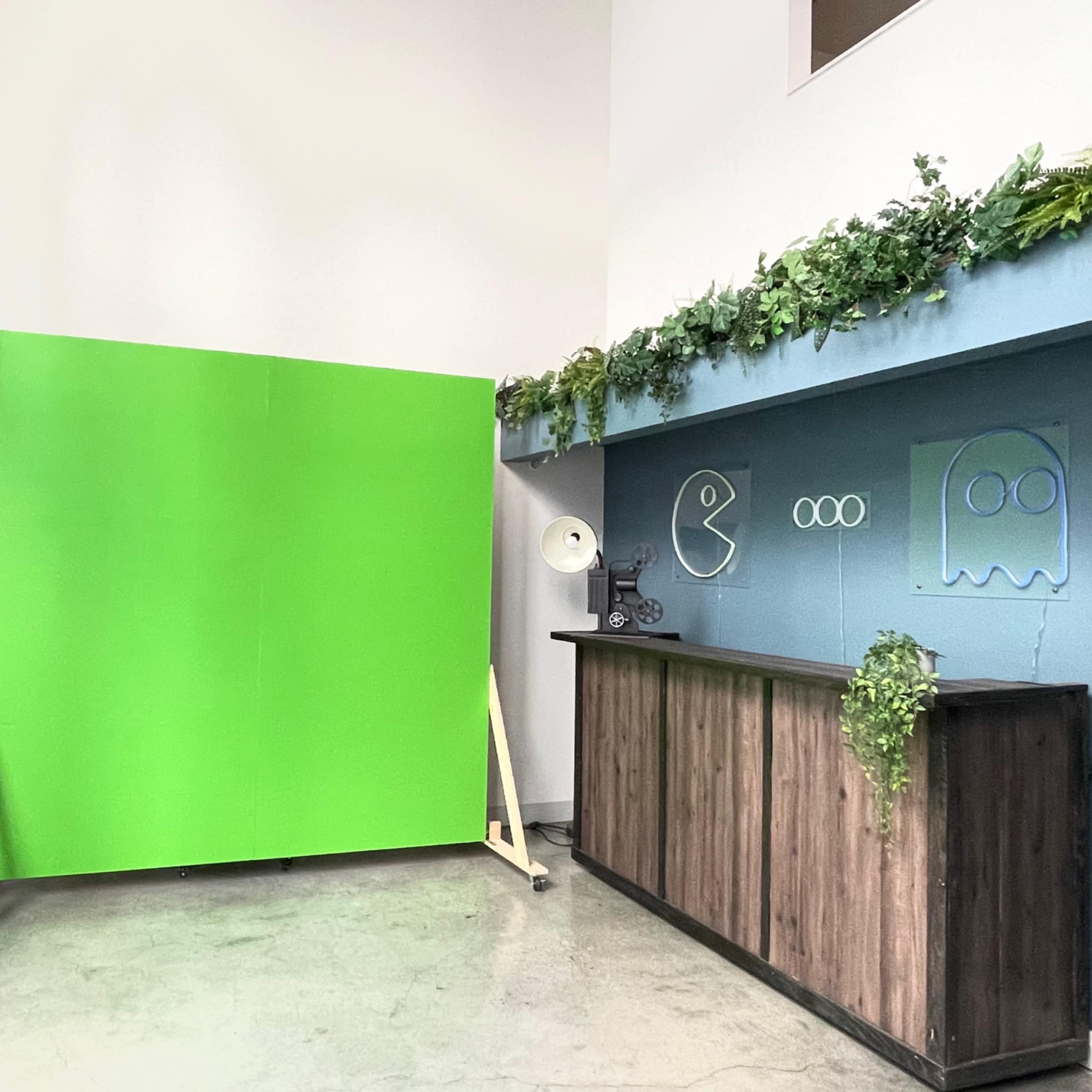 A room with a green backdrop, a wooden counter, a plant shelf, and decorative elements on the wall.