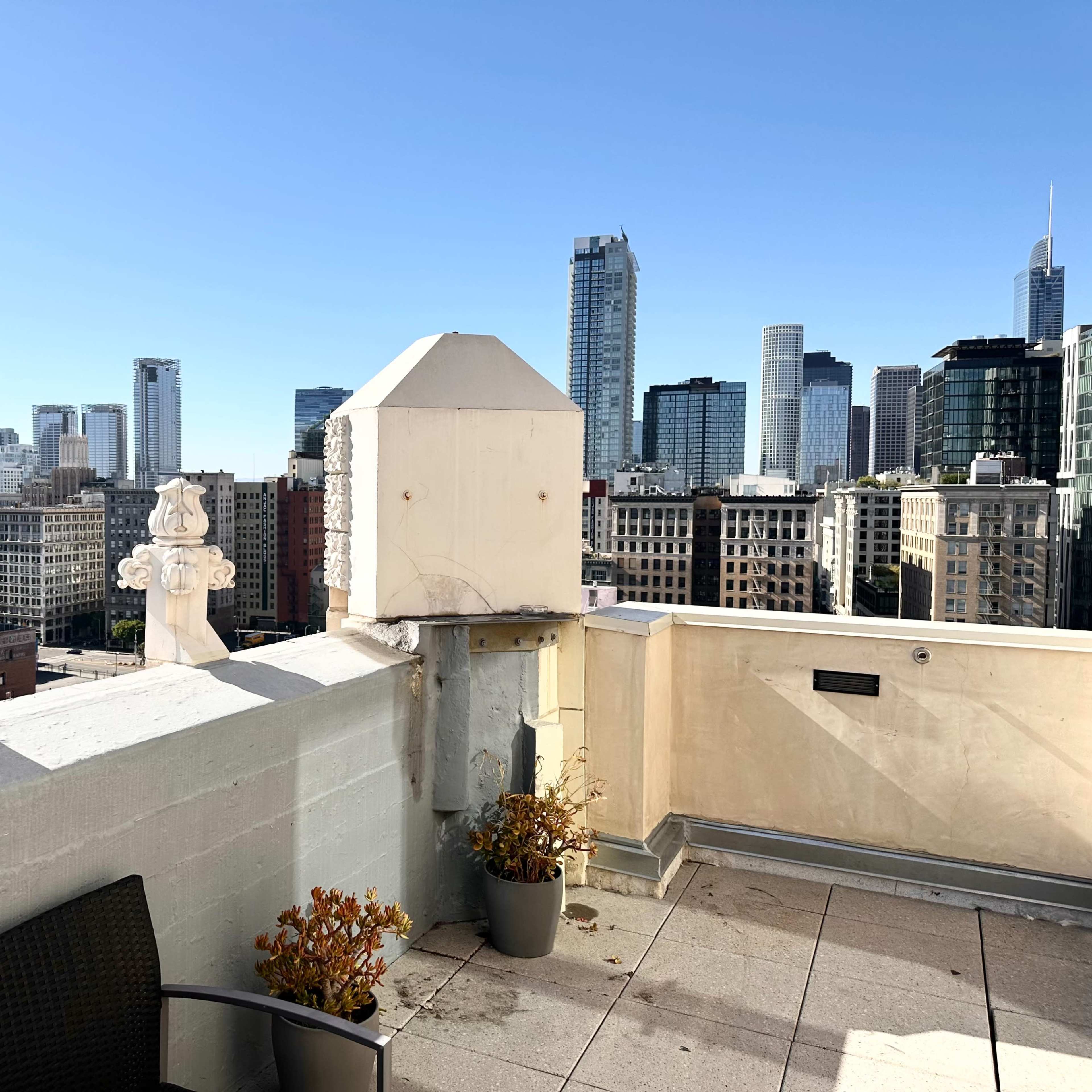 A rooftop view of a city skyline with modern buildings and decorative elements on the edge of the roof.