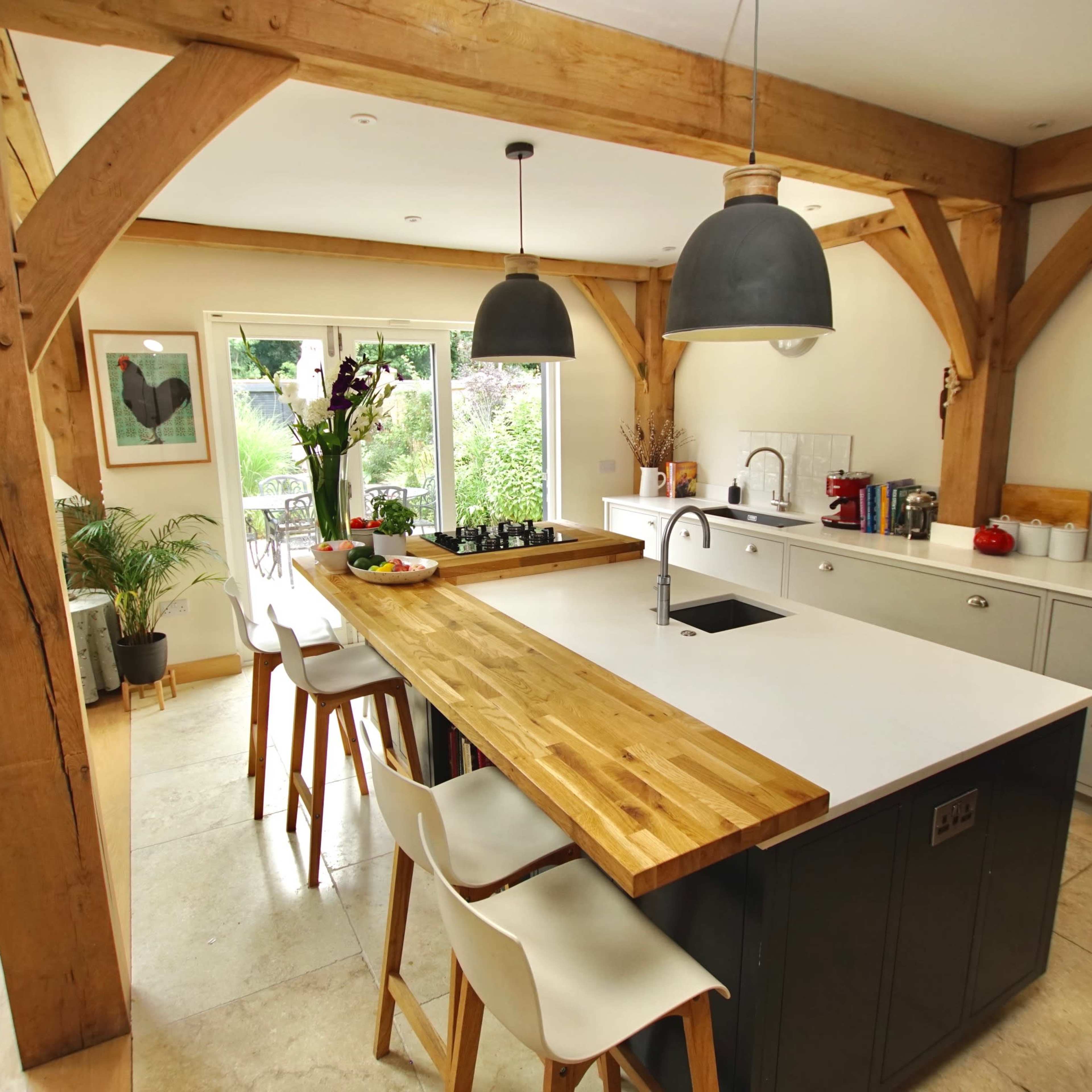 A modern kitchen with a central wooden island, gray cabinetry, and large pendant lights hanging above.
