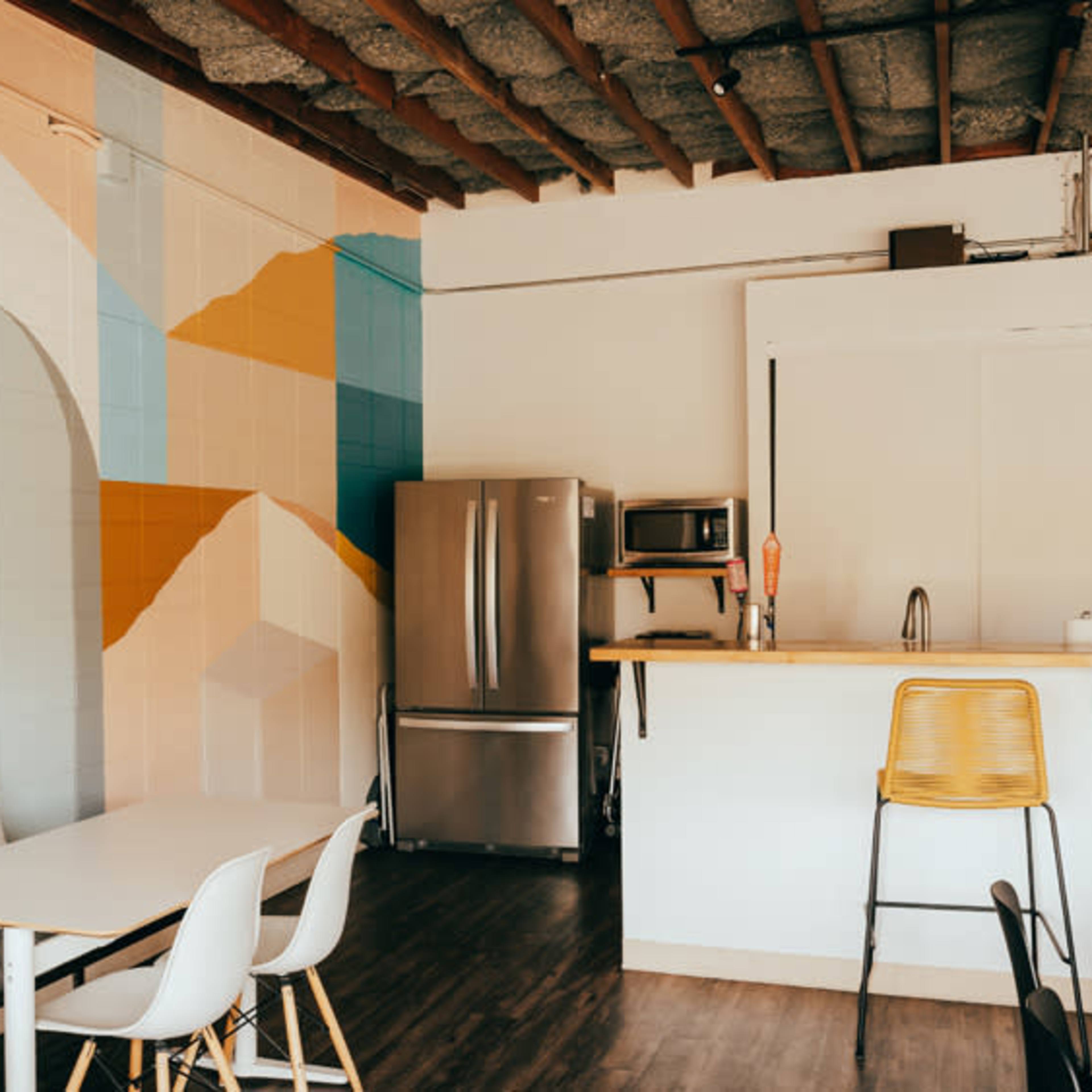 A modern kitchen area featuring a colorful mural on the wall, stainless steel appliances, and light wooden countertops.