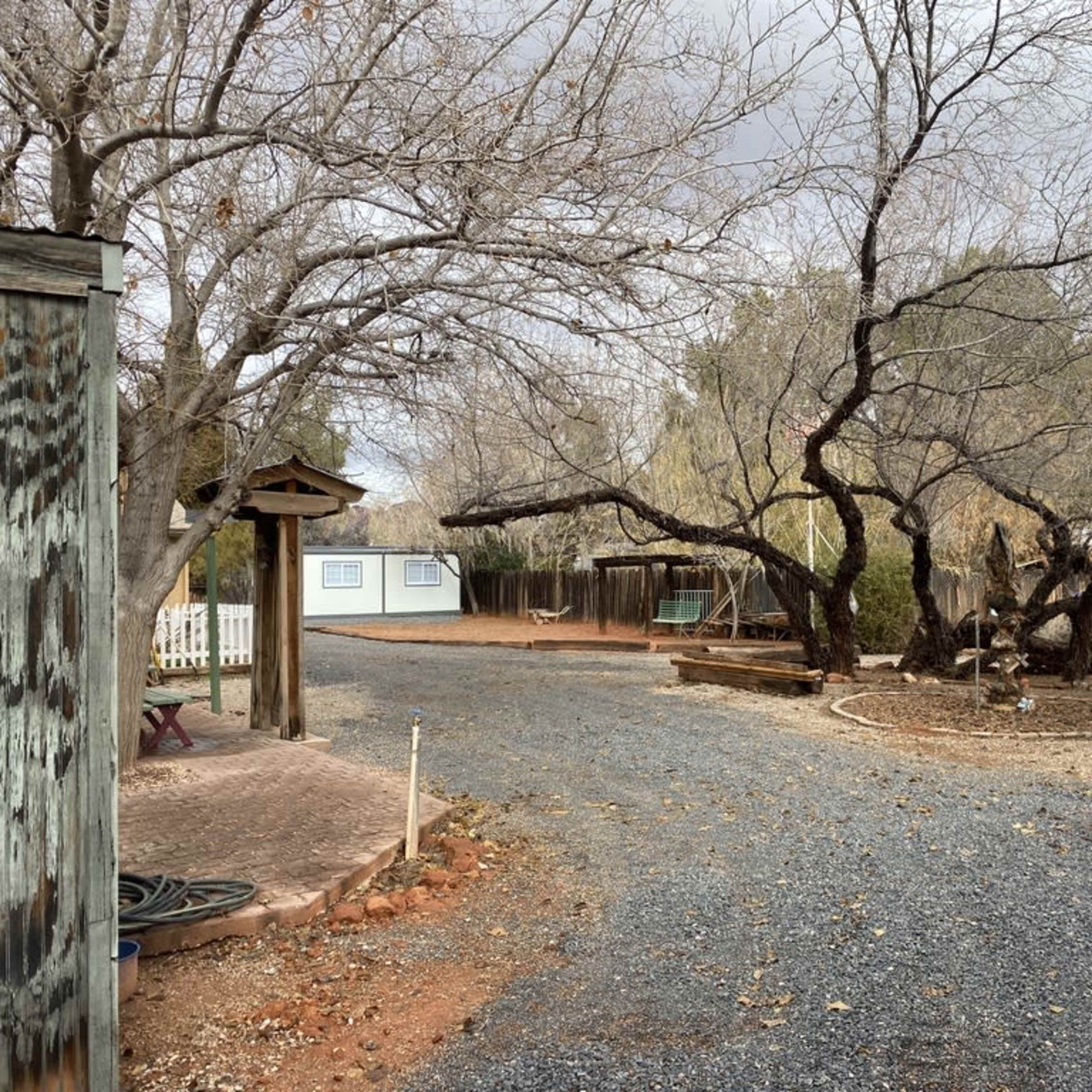 A gravel path winding through a sparse landscape with bare trees and a few structures in the background.