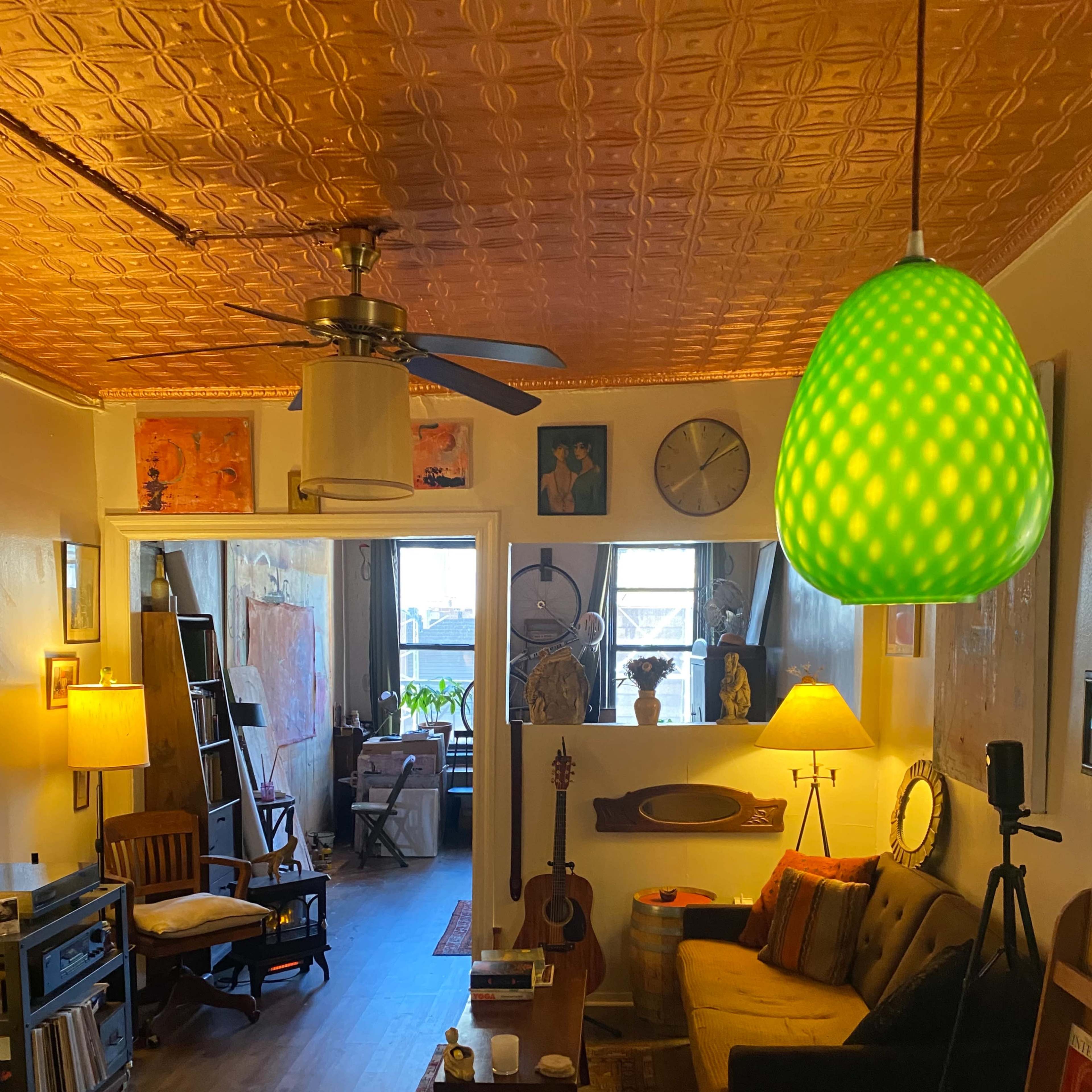 A cozy living room with variegated seating, a green pendant light, and various decorative items on display.