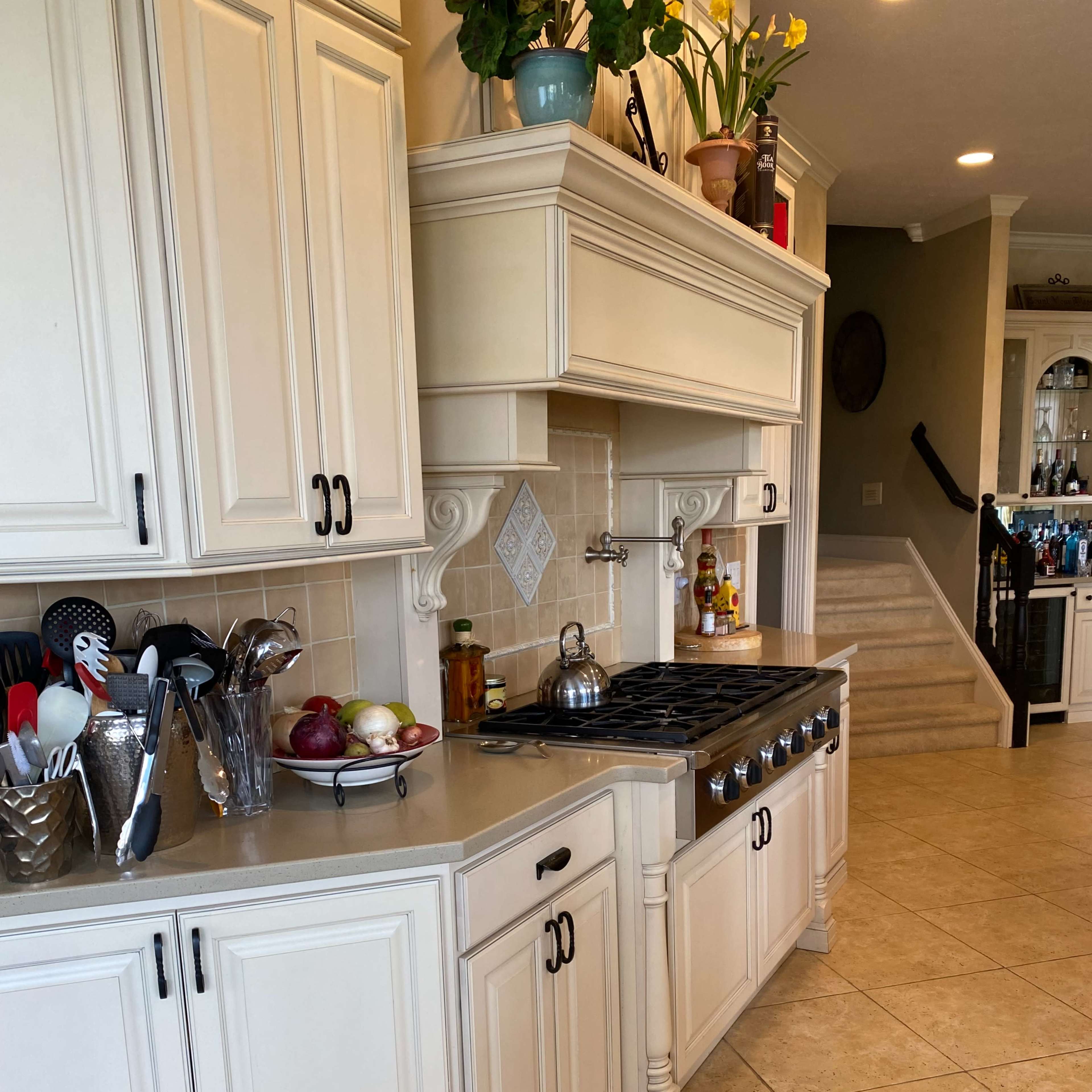 A spacious kitchen featuring light-colored cabinetry, a large gas stove, and various utensils arranged on the countertop.