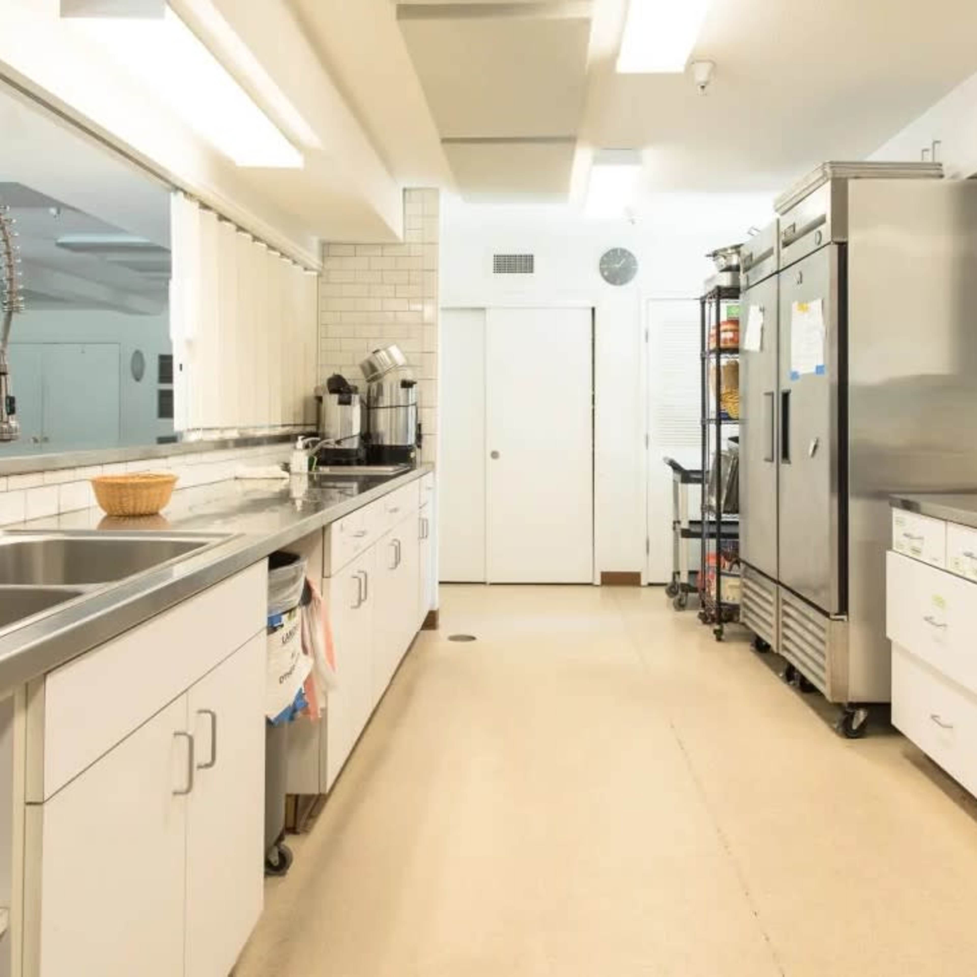 A clean, modern kitchen with stainless steel appliances, white cabinets, and a long counter space.