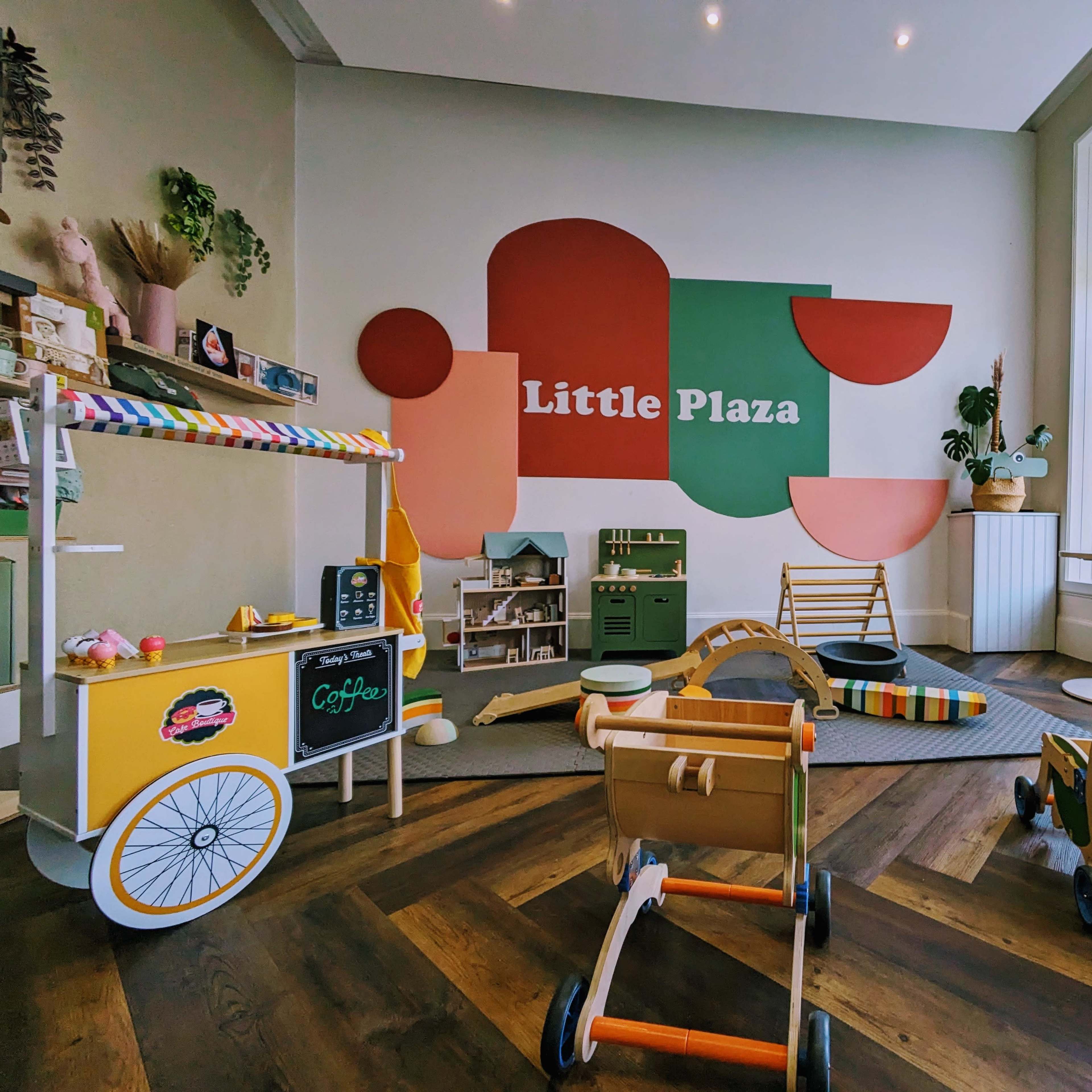 A brightly lit playroom featuring colorful wall art, various children's toys, and playful furniture arranged around a wooden floor.