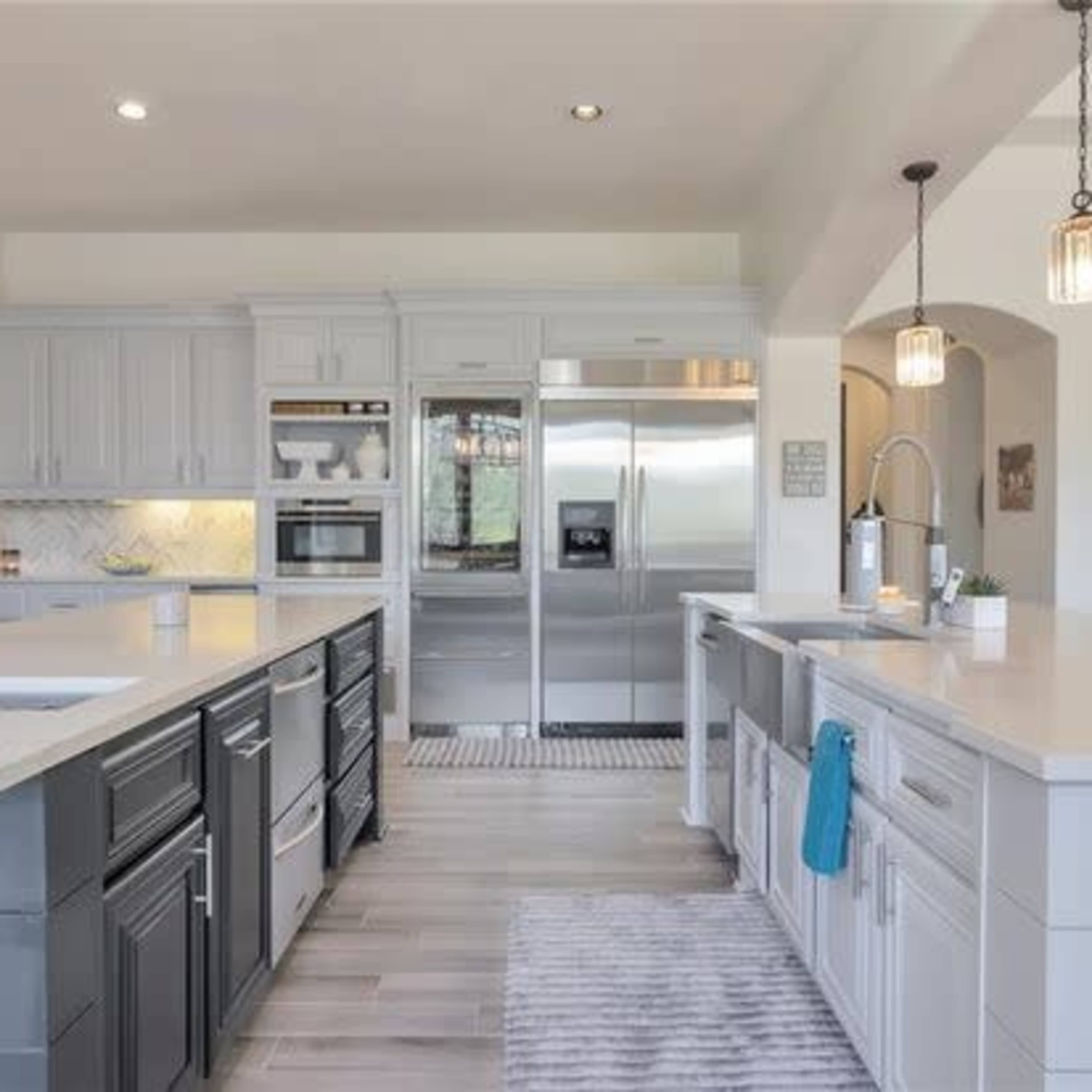 A modern kitchen featuring stainless steel appliances, a large island with seating, and light-colored cabinetry.