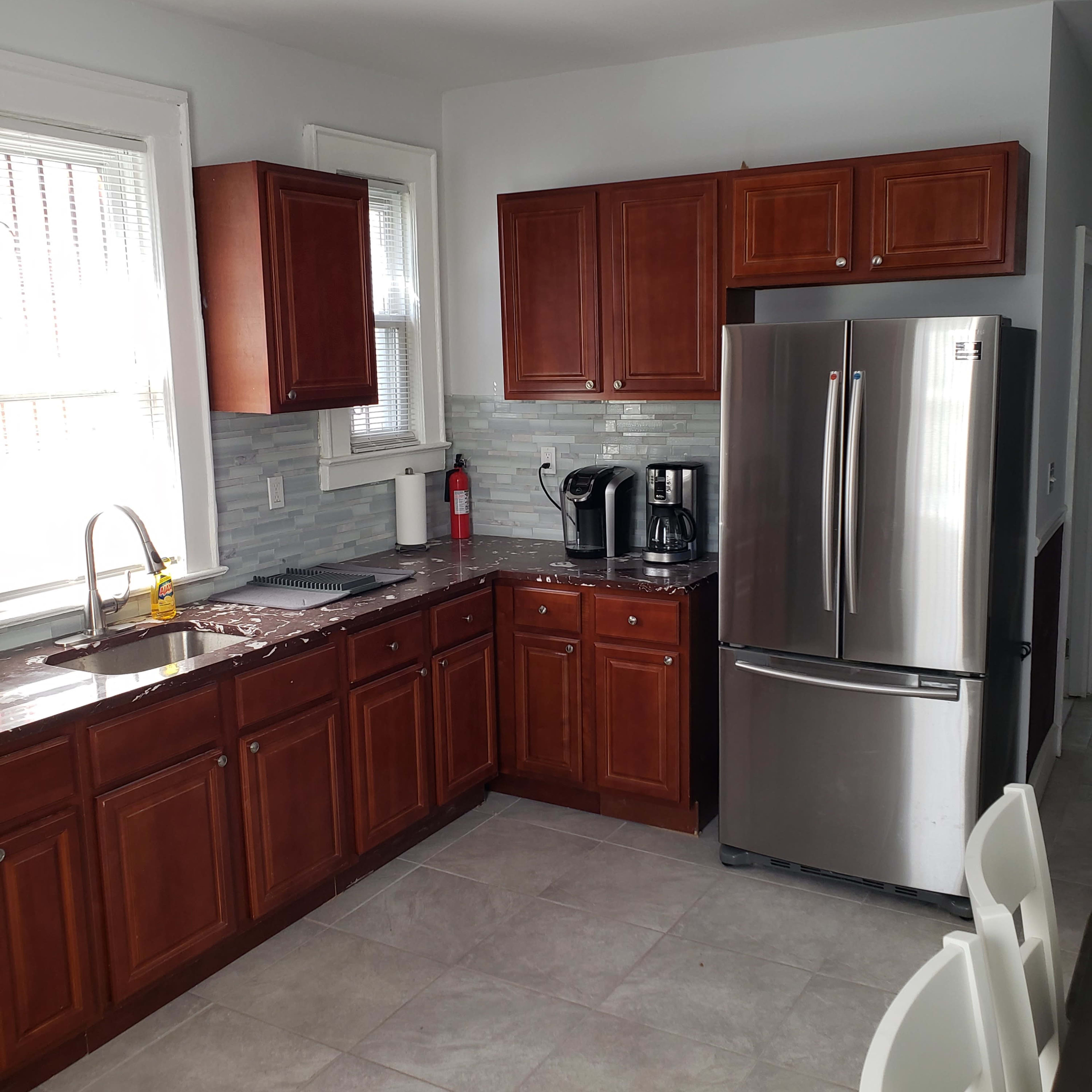 The kitchen features dark wood cabinets, stainless steel appliances, and a grey tile backsplash.