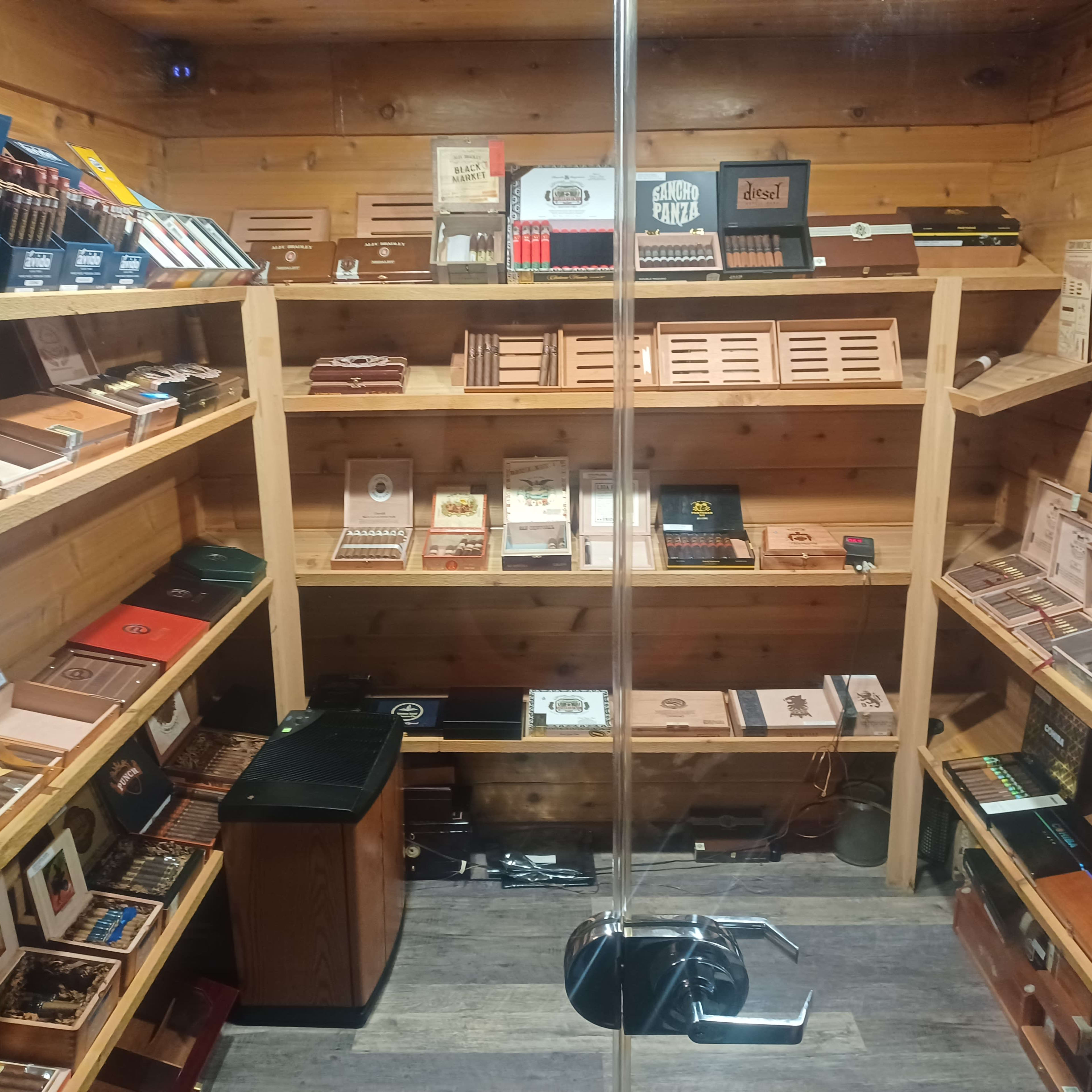 An indoor display of various cigar boxes neatly organized on wooden shelves in a private storage area.