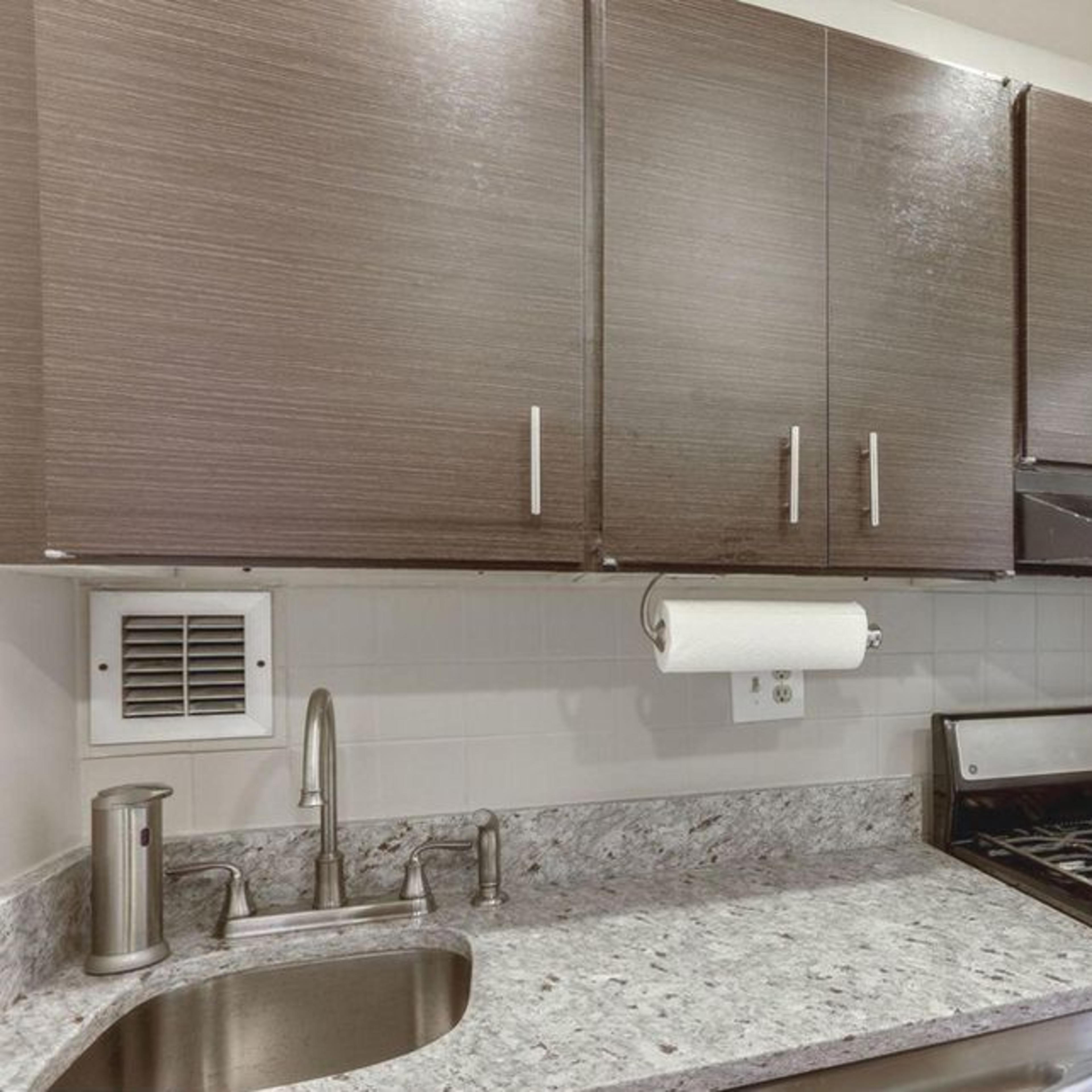 A compact kitchen with dark cabinets, a stainless steel stove, and a granite countertop.