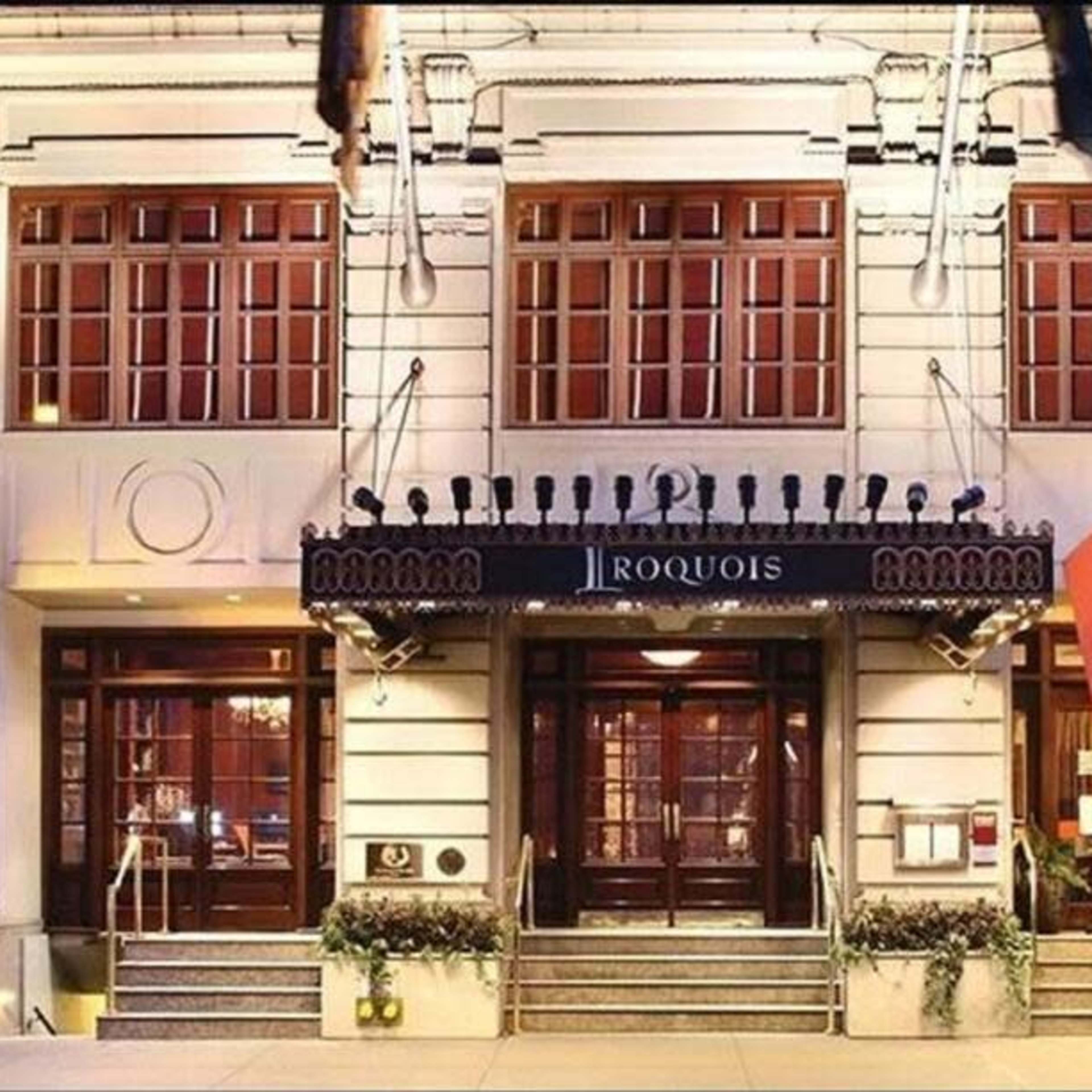 The entrance of the Iroquois Hotel, featuring large wooden doors and a canopy with the hotel's name.