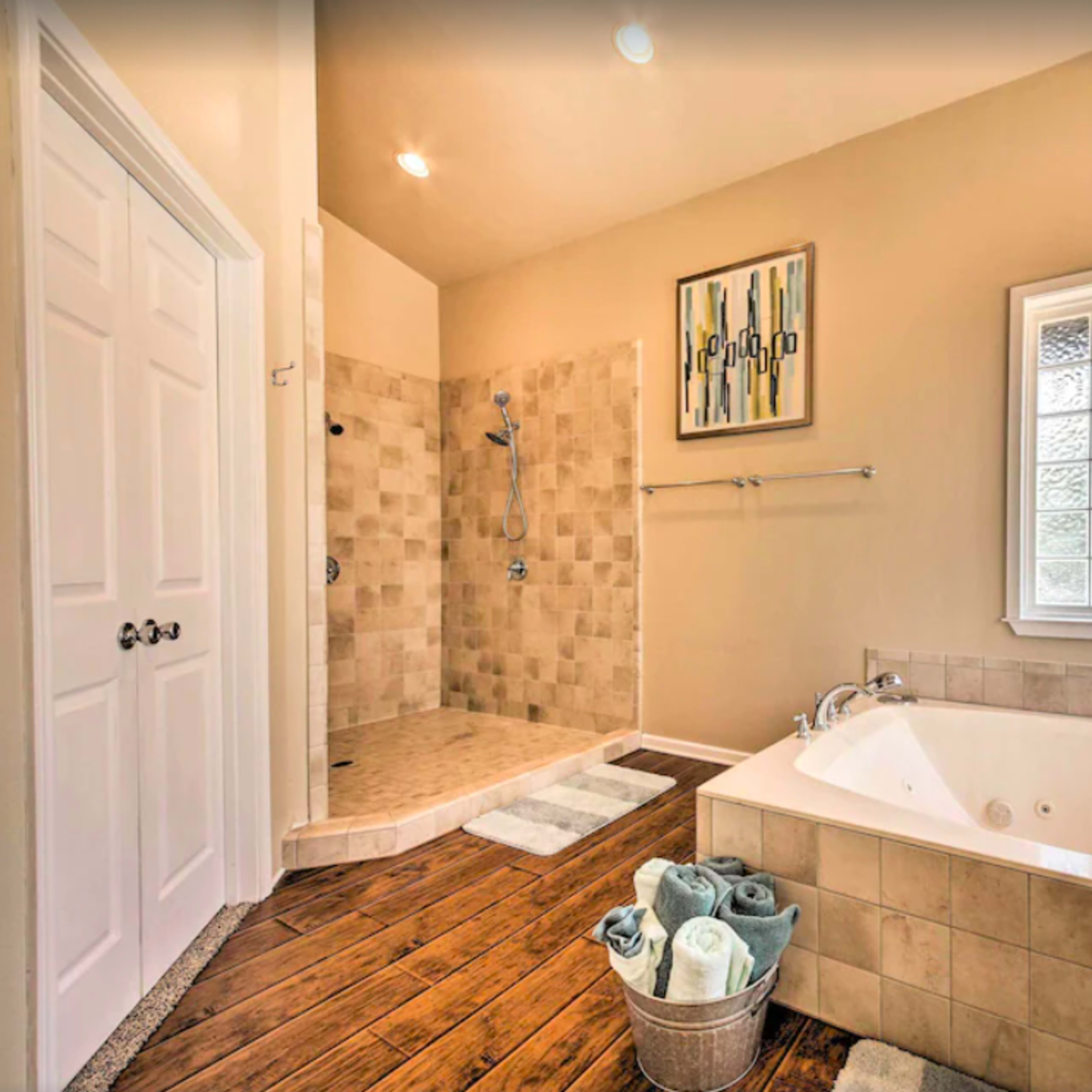 A bathroom featuring a large soaking tub, a separate shower area with glass blocks, and neatly arranged towels in a basket.
