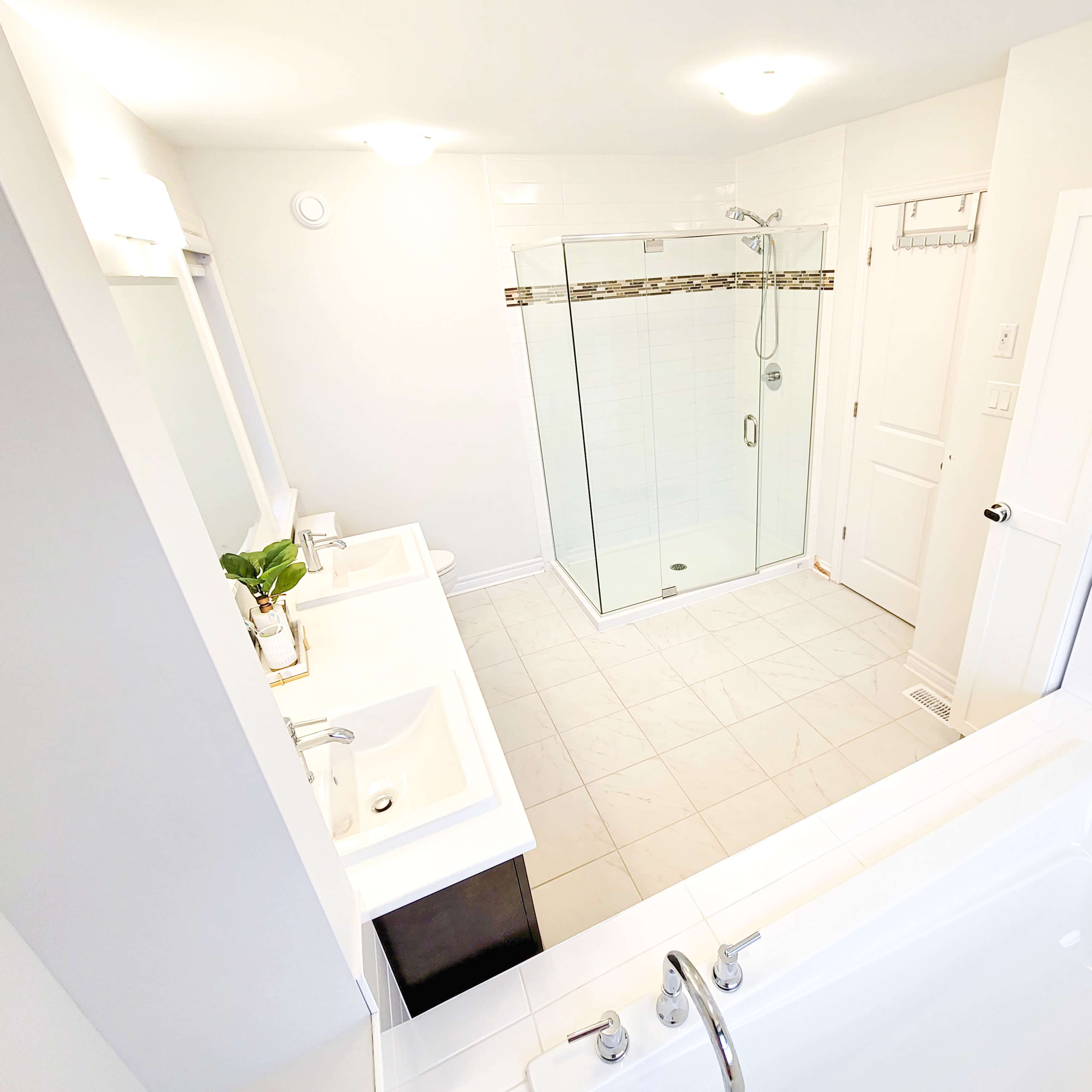 A modern bathroom with dual sinks, a glass-enclosed shower, and a freestanding bathtub.