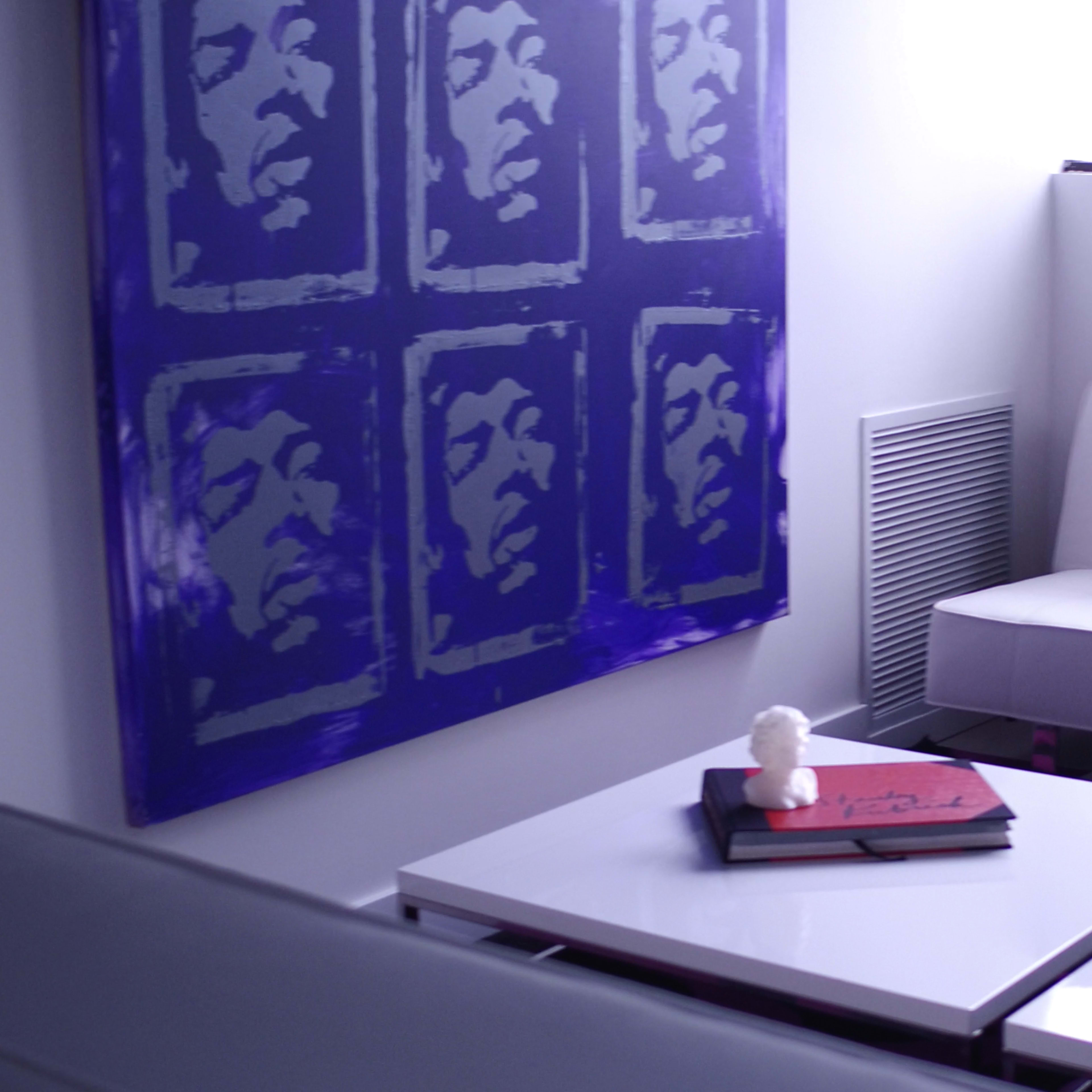 A modern living space featuring a white sofa, a coffee table with books, and a large purple artwork on the wall.
