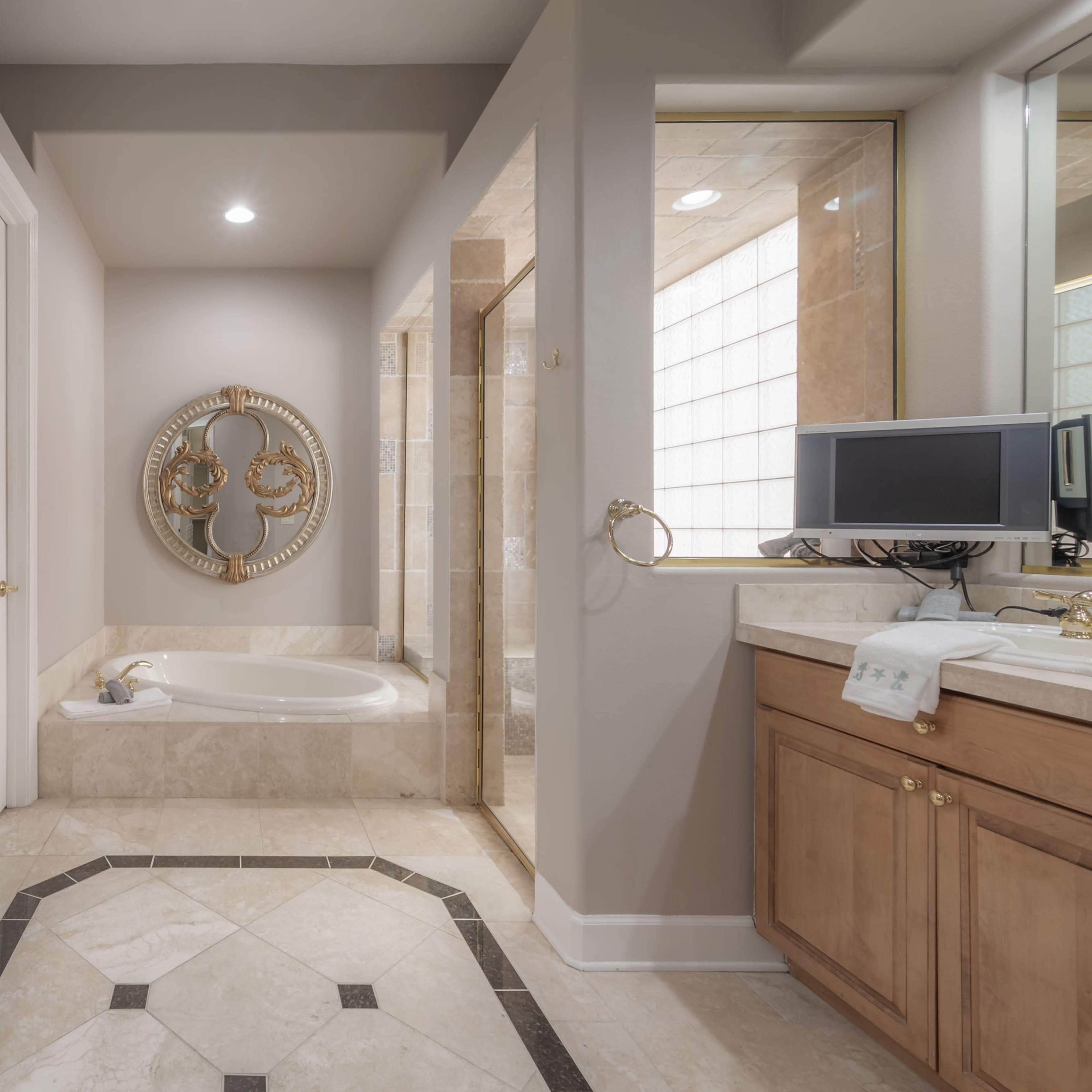 A spacious bathroom with a large bathtub, wooden cabinets, and a glass-enclosed shower.