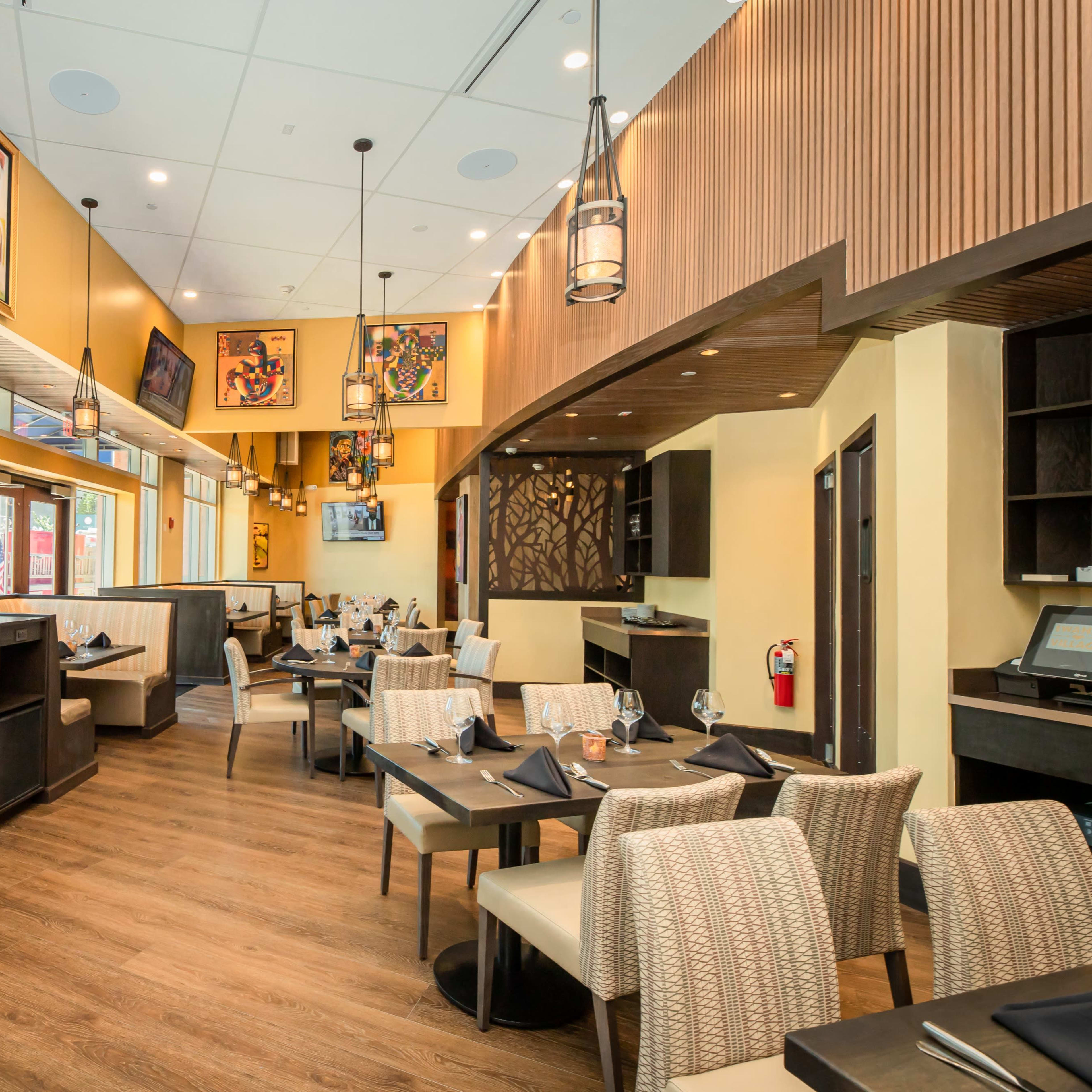 An interior view of a restaurant featuring booth seating, wooden floors, and decorative wall art.