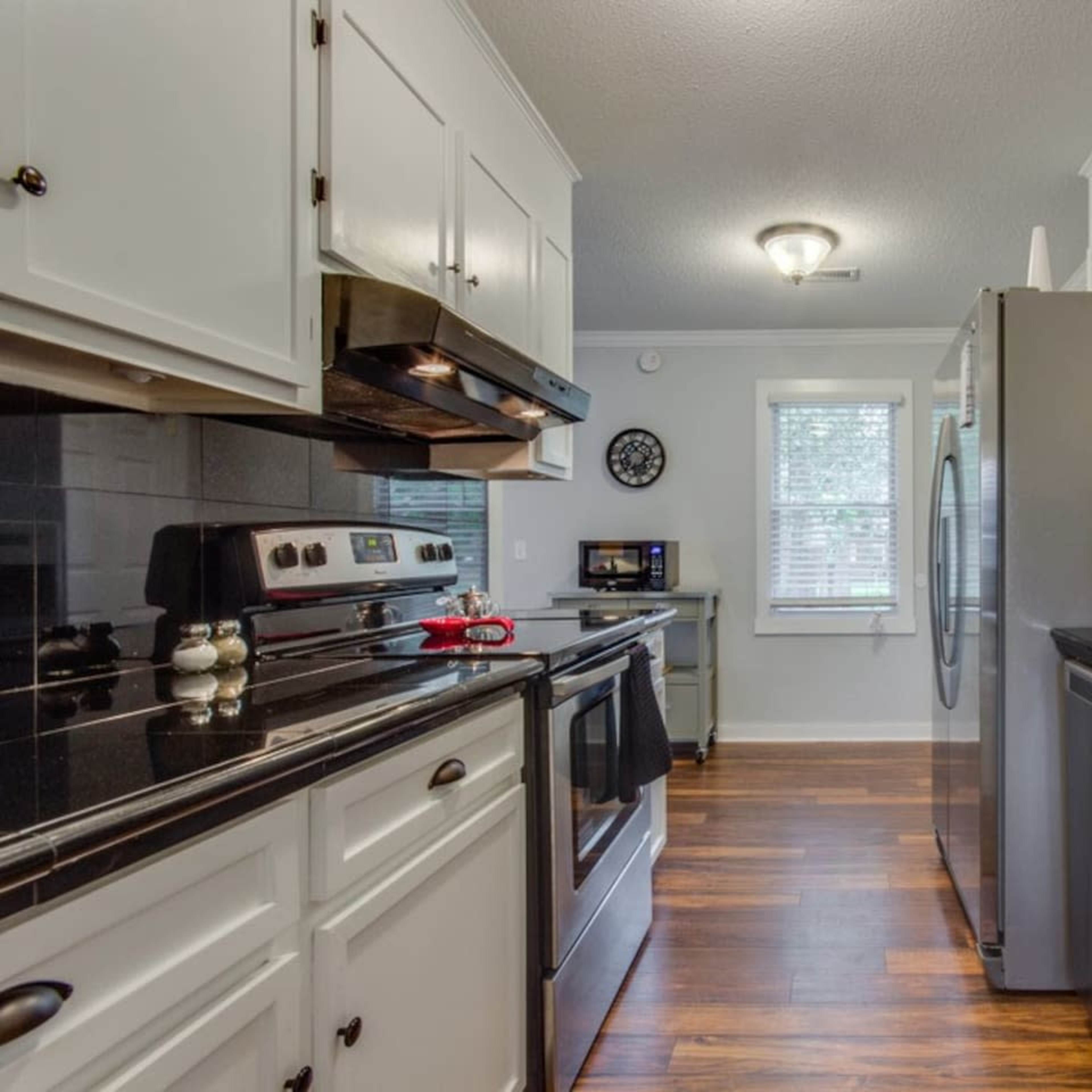A modern kitchen with white cabinets, stainless steel appliances, and dark countertops.
