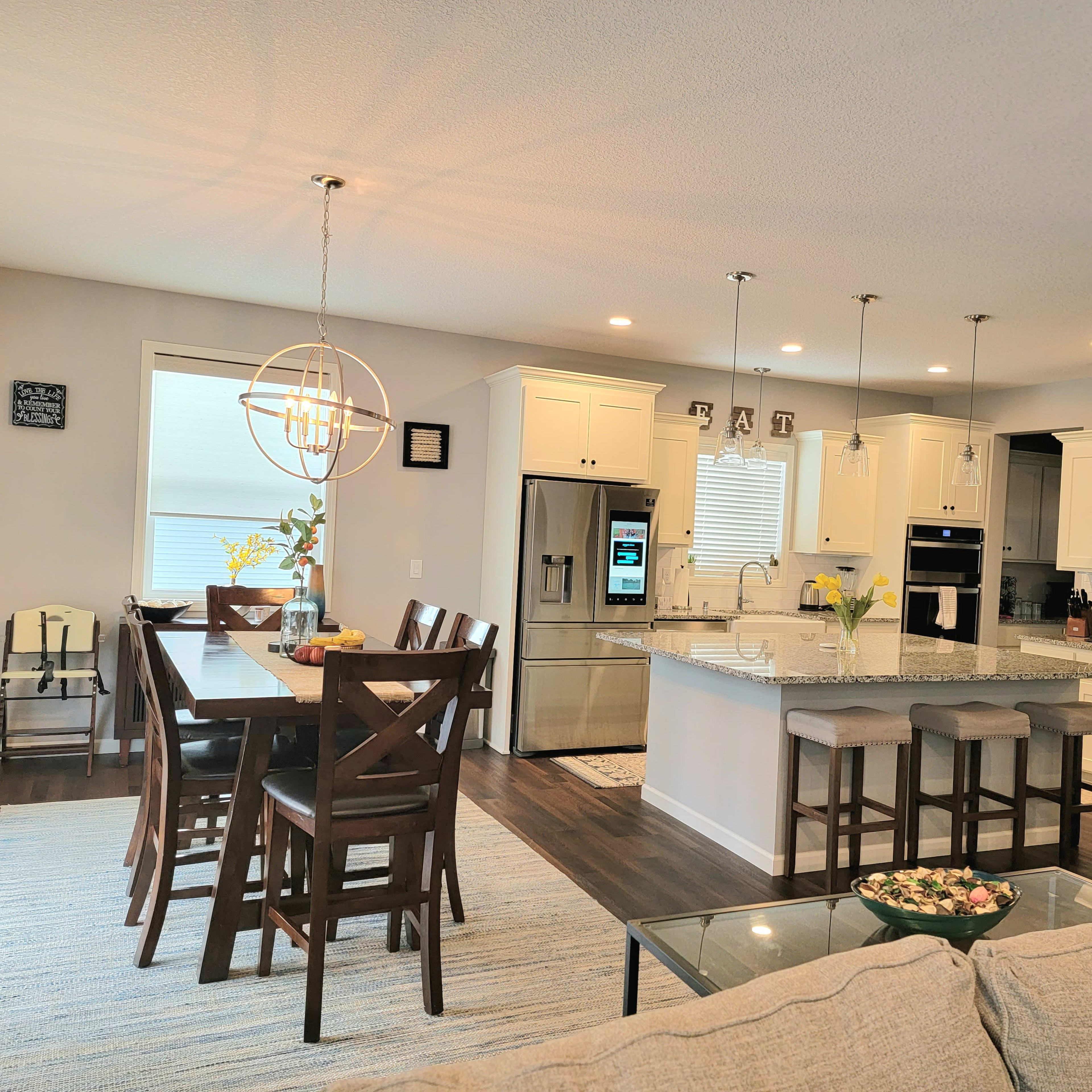 A modern kitchen and dining area with a large island, wooden dining table, and contemporary appliances.