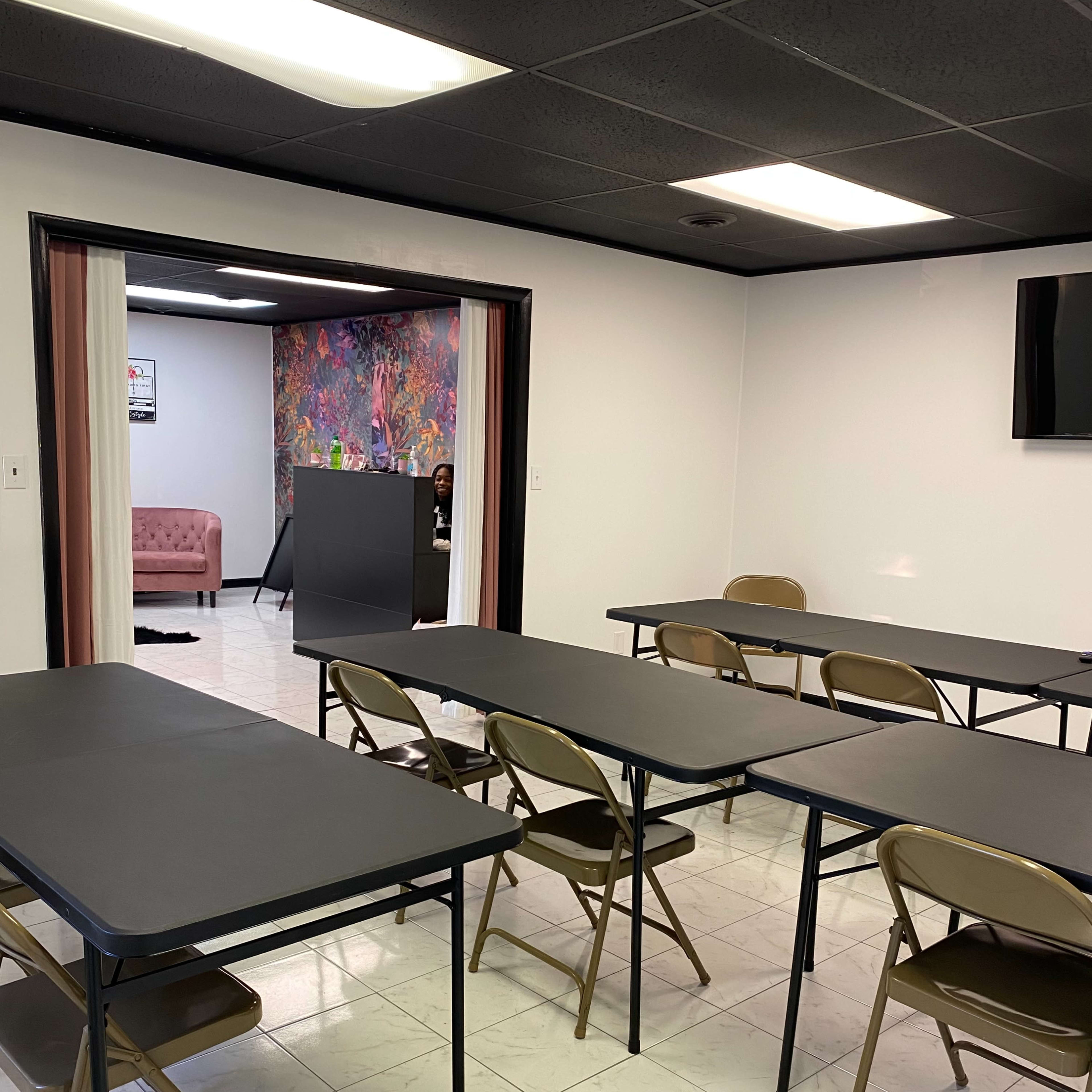 A room with several folding tables and chairs arranged in rows, featuring a colorful mural in the background.