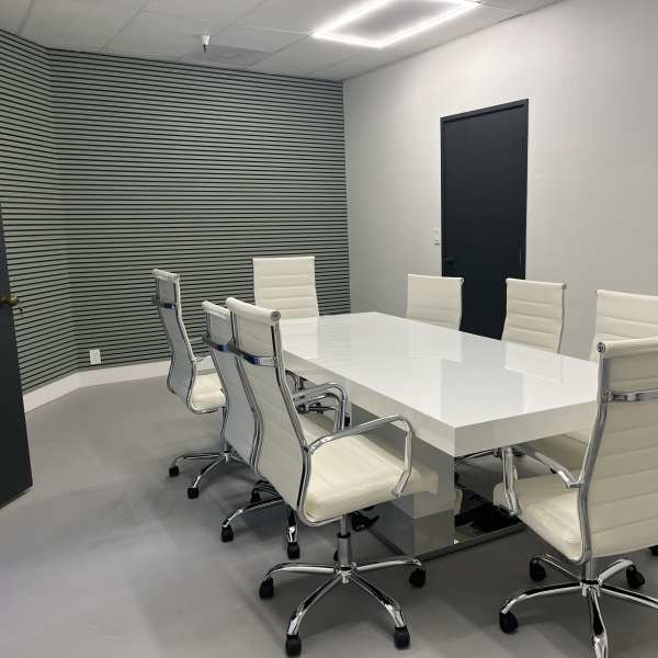 The conference room: a long white table ringed by white rolling chairs.