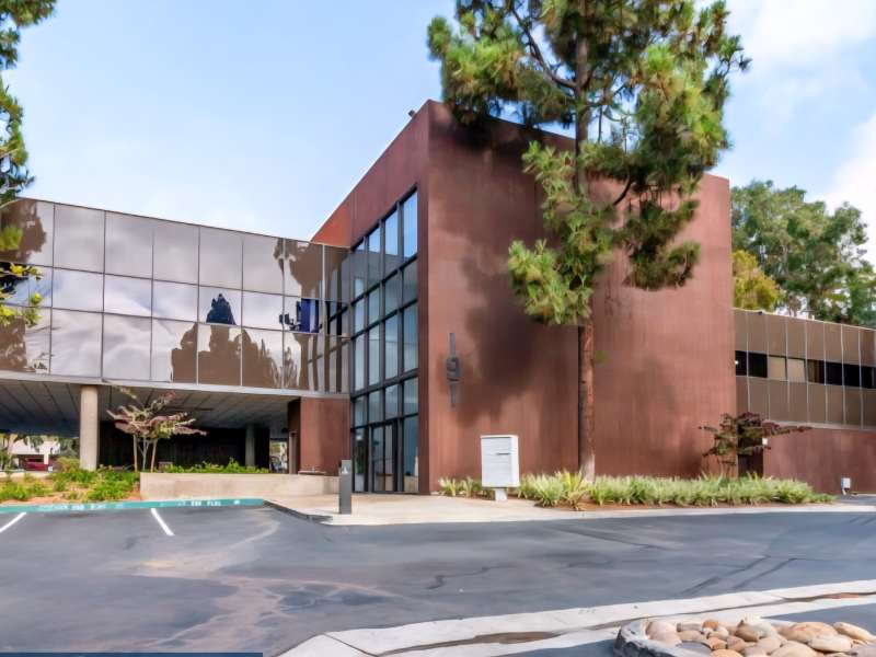 The exterior of building 191 — a two-storey glass and terracotta office building with an open lot in front.