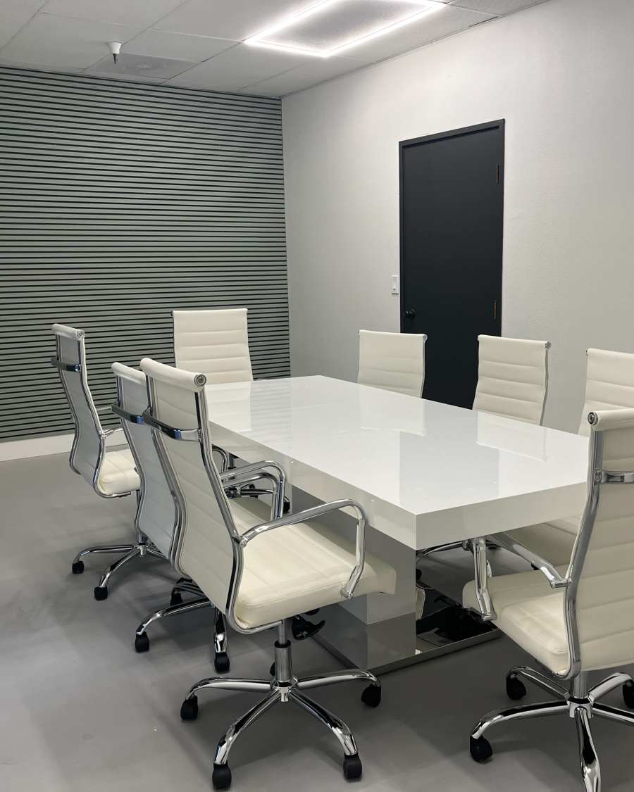 The conference room: a long white table ringed by white rolling chairs.