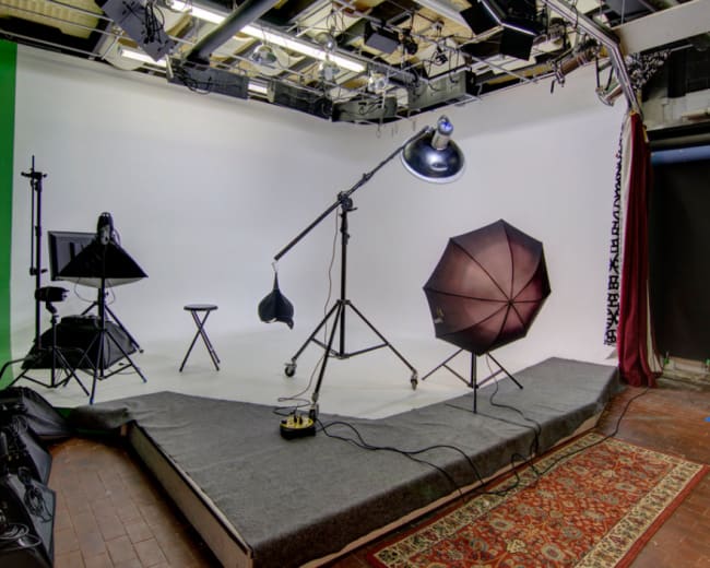 A photography studio setup with lighting equipment, a backdrop, and a patterned rug on the floor.