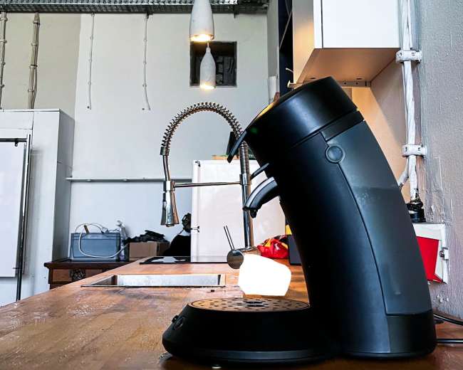 A black kettle is positioned on a wooden countertop in a modern kitchen with industrial elements.