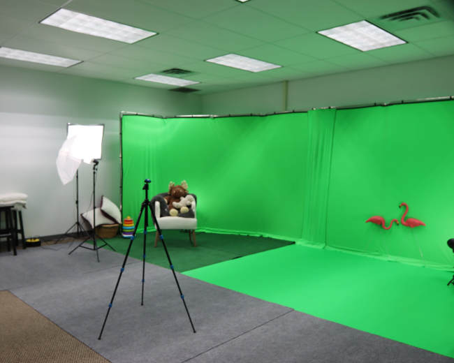 The image shows a green screen studio with a chair, a stuffed animal, lighting equipment, and a tripod.