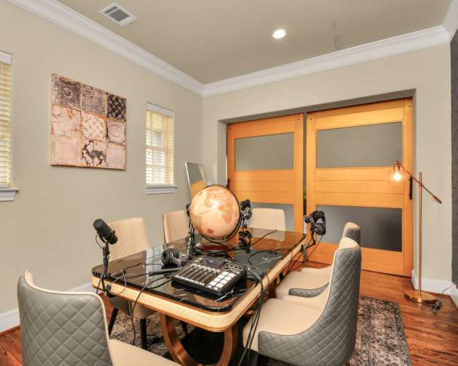 The image shows a modern conference room with a large table, microphones, a globe, and sliding wooden doors.