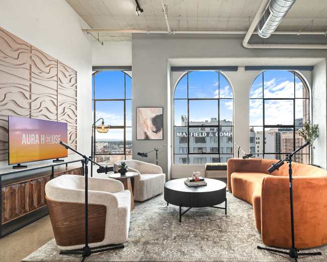 The image showcases a modern living room with large arched windows, stylish furniture including circular chairs and a coffee table, and decorative elements such as a television and a spiral staircase.